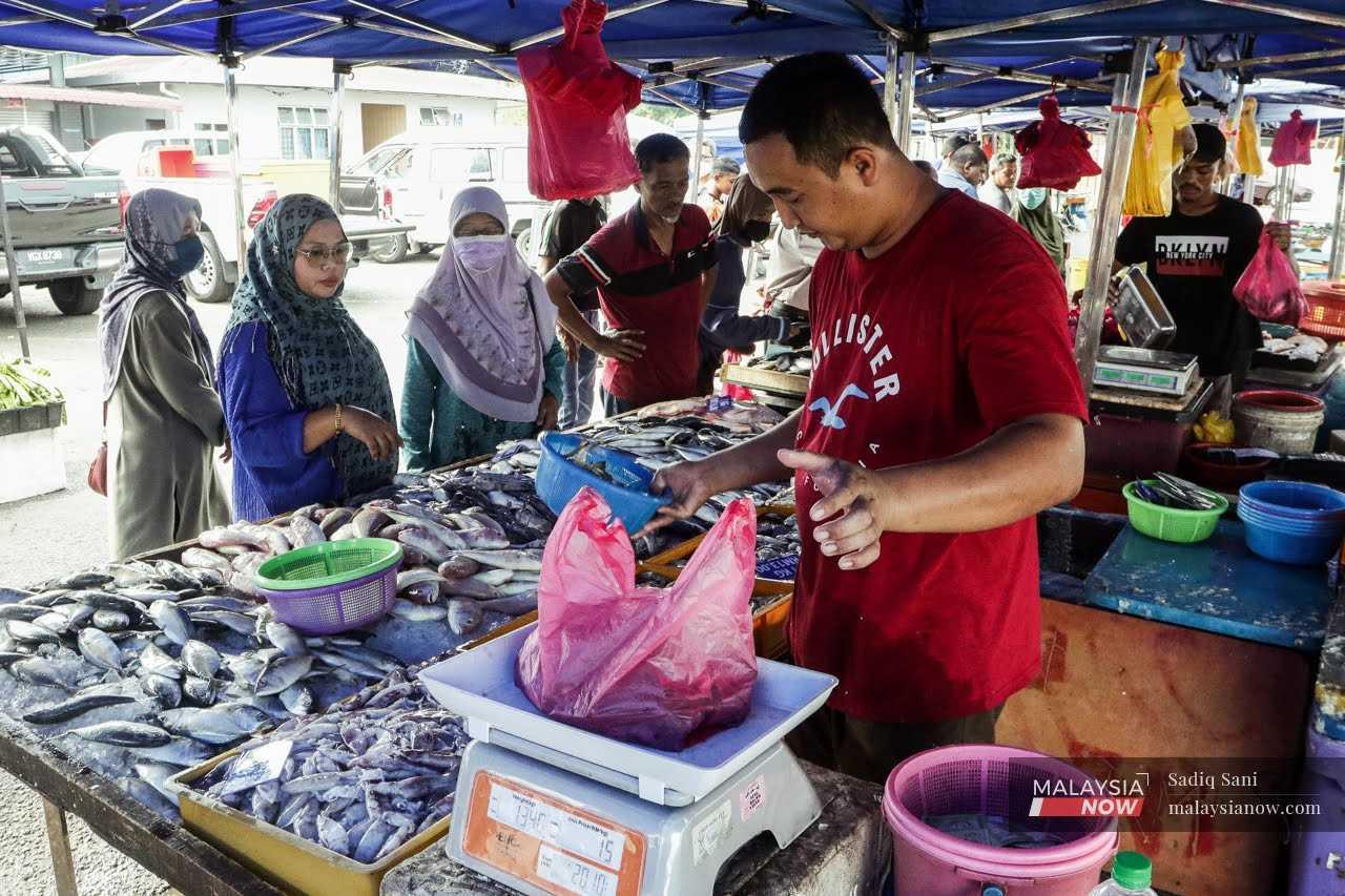 Peniaga menimbang makanan hasil laut untuk pelanggan di pasar basah di Tanjung Karang, Selangor, 4 Mei.