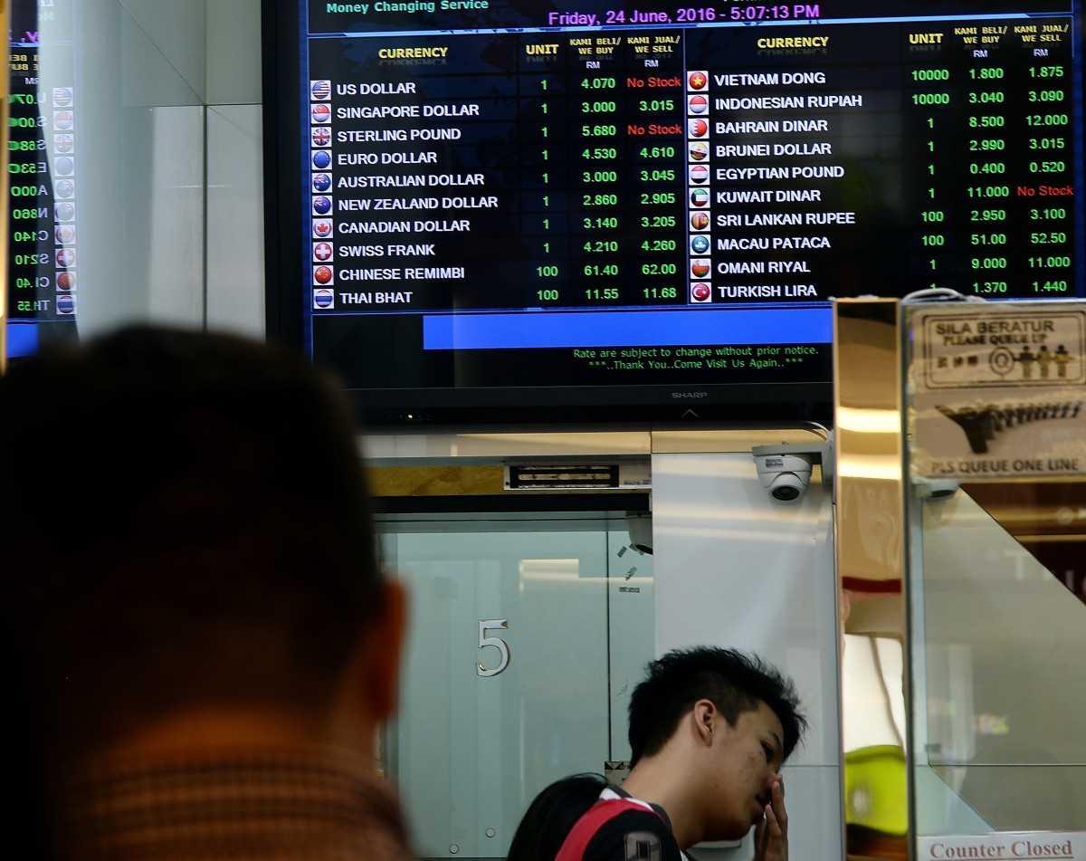 A man buys currency at a foreign exchange store in Kuala Lumpur on June 24, 2016. Photo: AFP