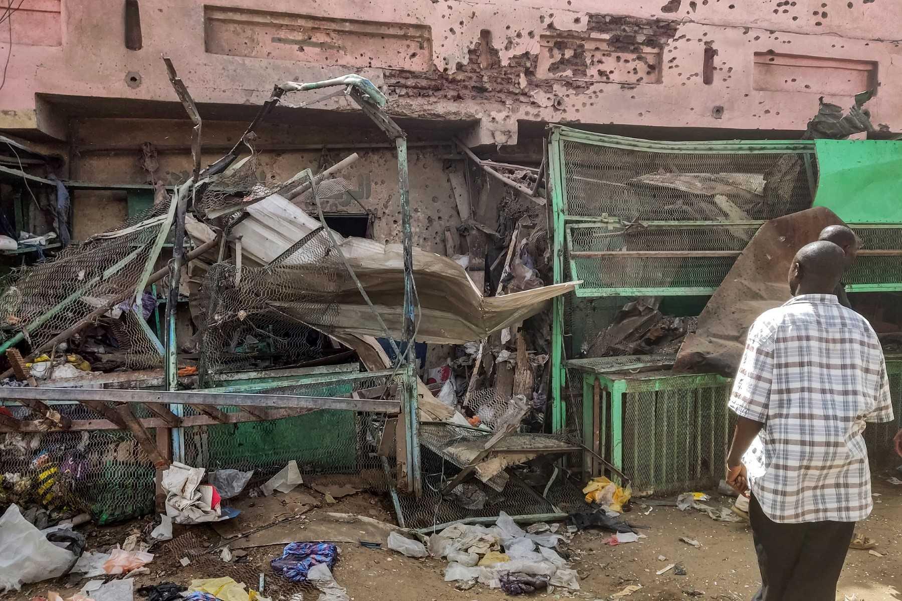 People walk past a medical centre building riddled with bullet holes at the Souk Sitta (Market Six) in the south of Khartoum on June 1. Photo: AFP