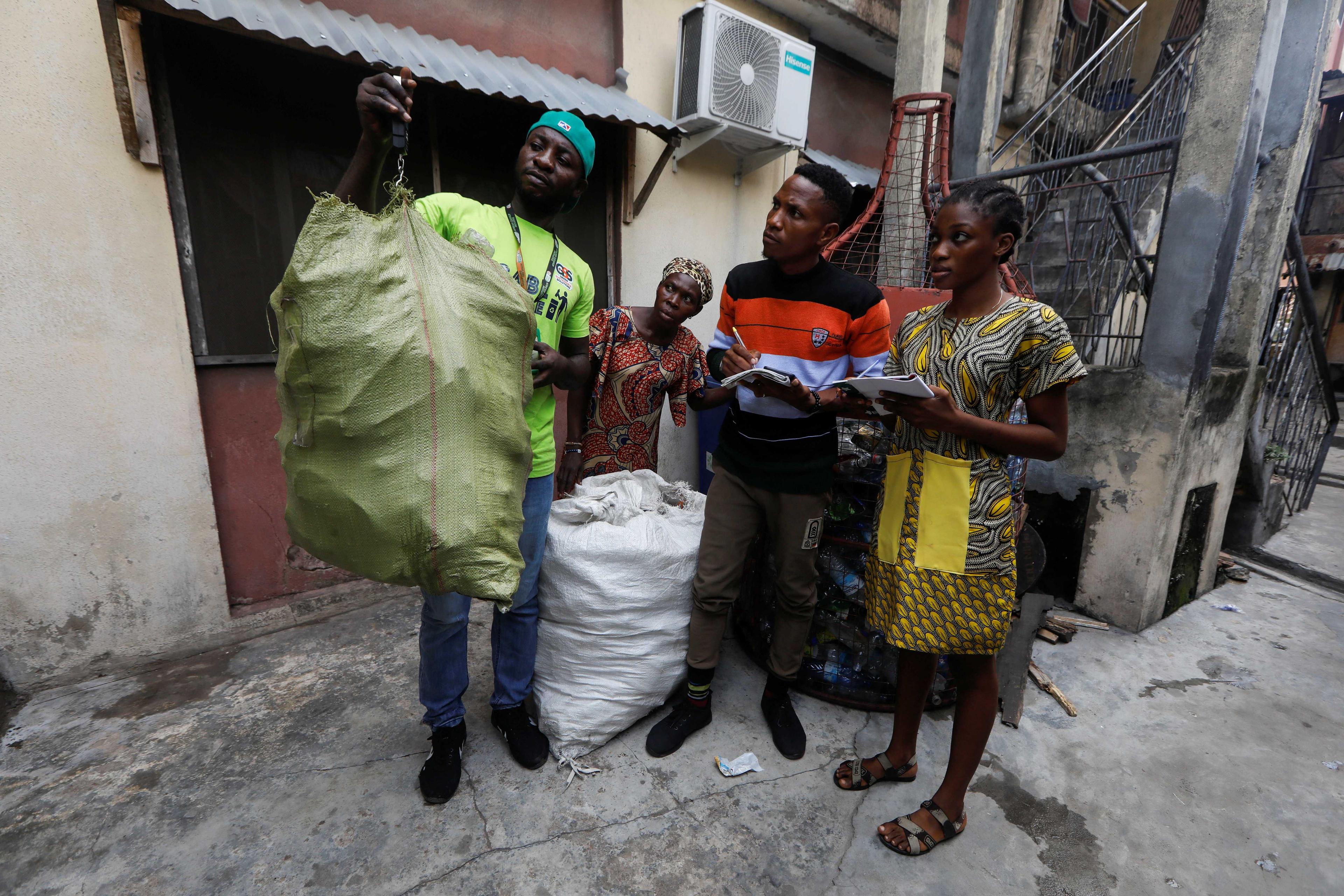 A recyclable waste collector weighs a sack of plastic containers submitted by a parent of a student of My Dream Stead, a low-cost school that accepts recyclable waste as payment, in Ajegunle, Lagos, Nigeria May 19. Photo: Reuters