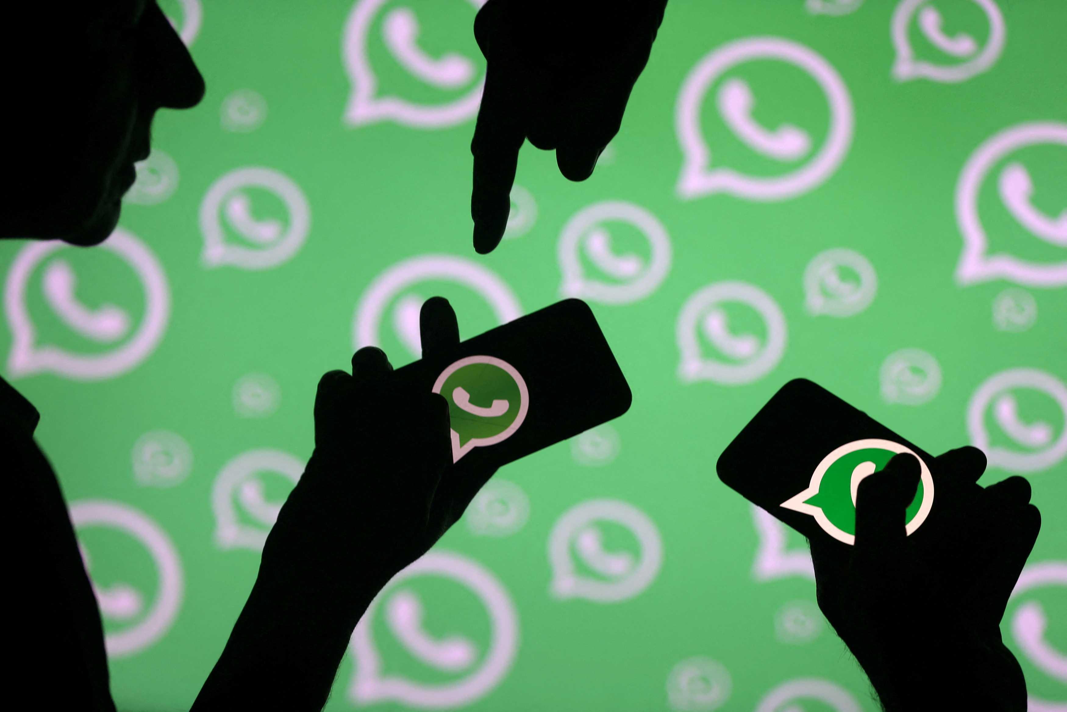 Men pose with smartphones in front of displayed WhatsApp logo in this illustration Sept 14, 2017. Photo: Reuters