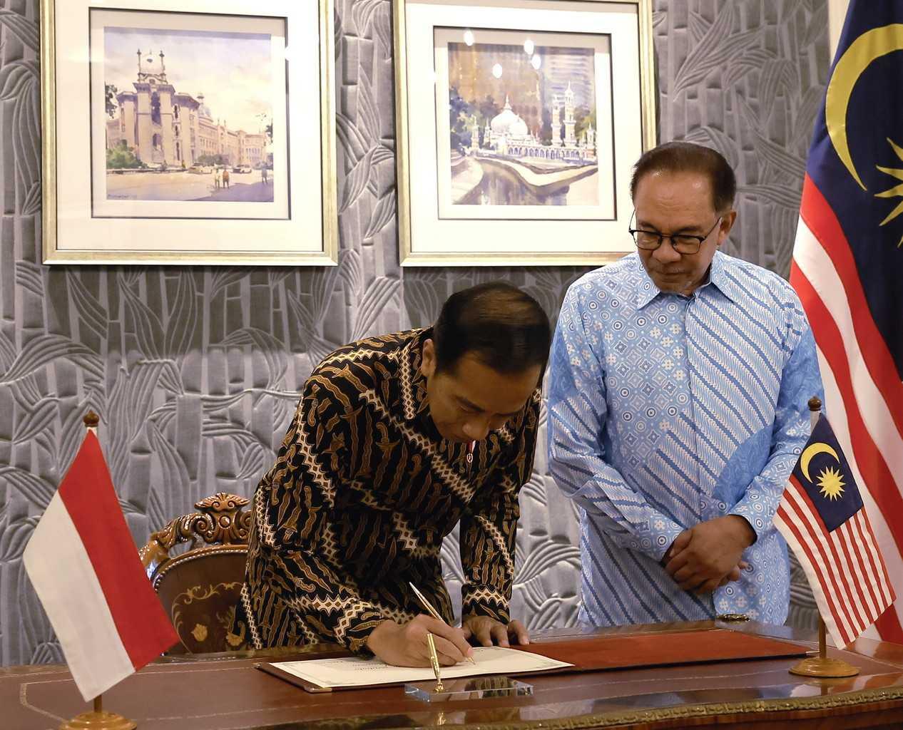 Indonesian President Joko Widodo, accompanied by Prime Minister Anwar Ibrahim, signs the guest book on the second day of his working visit to Malaysia, at Seri Perdana in Putrajaya, June 8. Photo: Bernama
