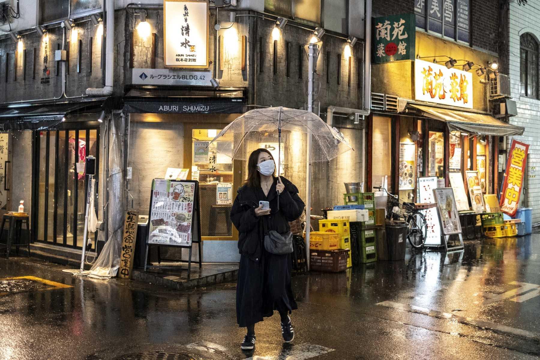 Seorang wanita berjalan di sepanjang jalan ketika hujan petang turun di Tokyo pada 18 April 2022. Gambar: AFP