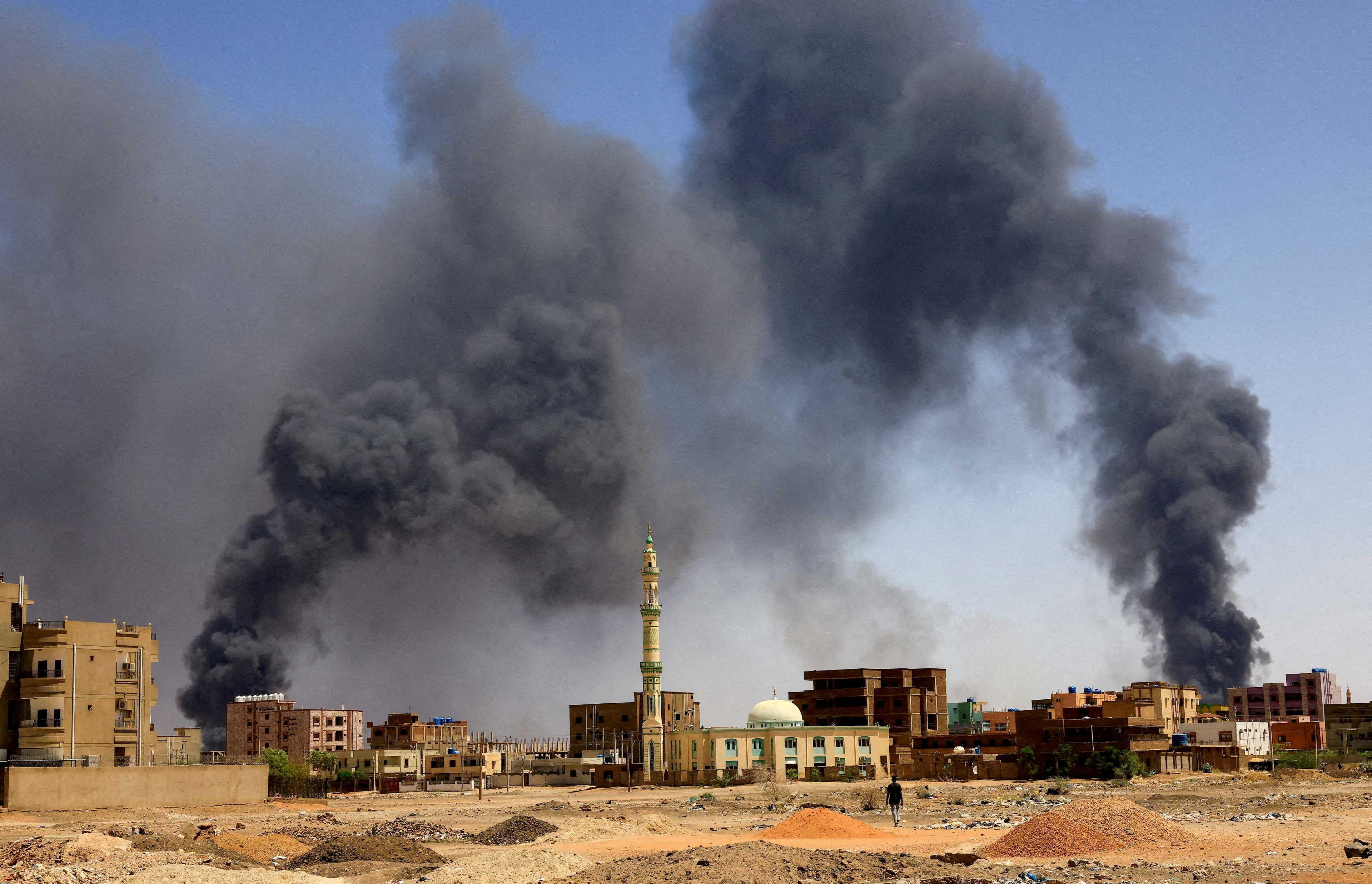 A man walks while smoke rises above buildings after aerial bombardment, during clashes between the paramilitary Rapid Support Forces and the army in Khartoum North, Sudan, May 1. Photo: Reuters