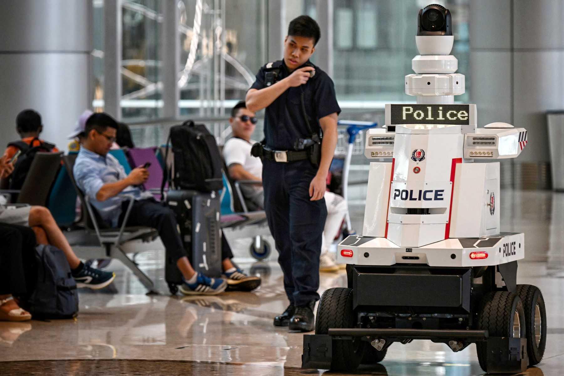 A Singapore Police Force officer patrols with a police robot at Changi Airport in Singapore on June 15. Photo: AFP
