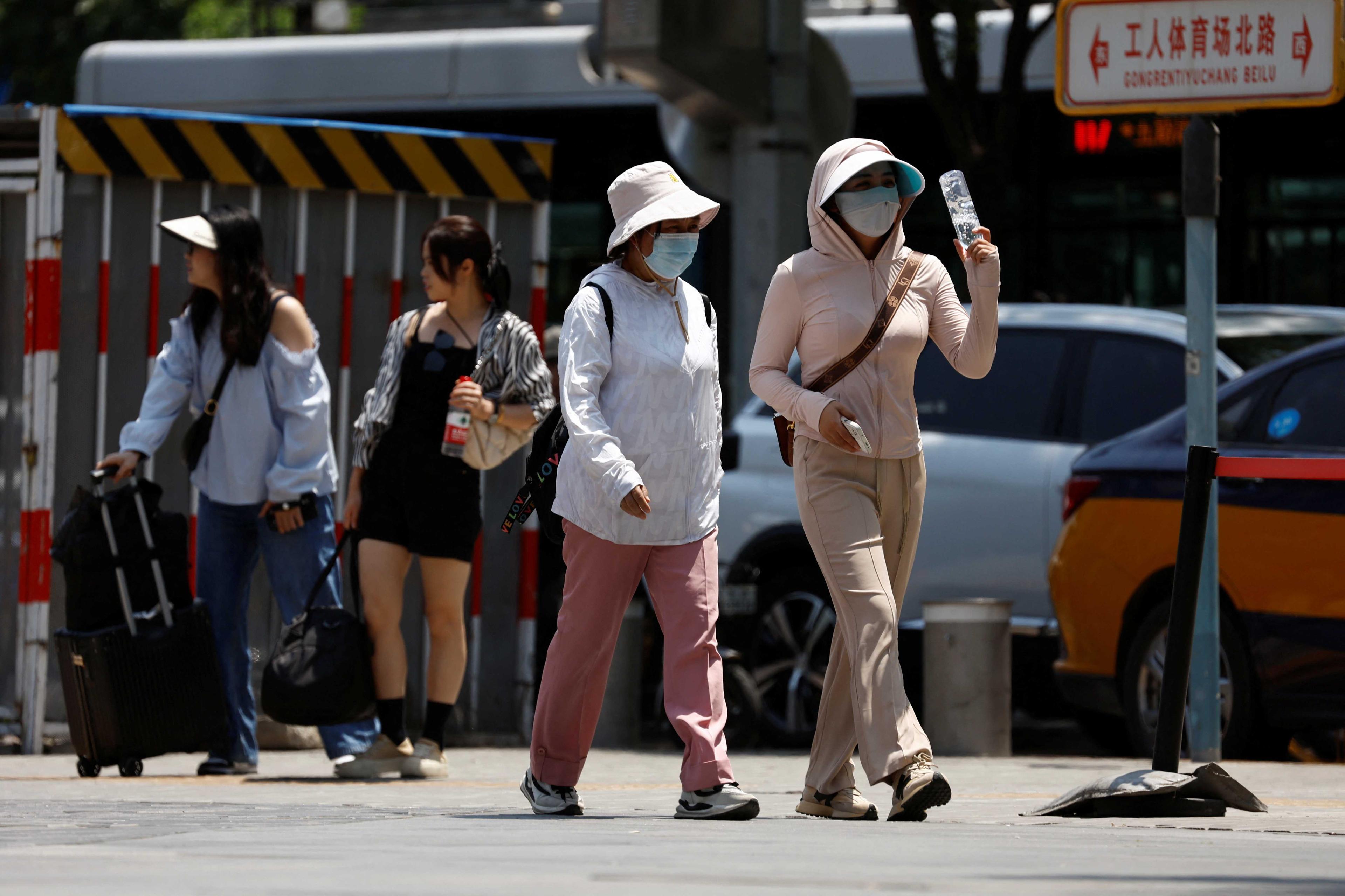 People wearing sun-protective clothing walk on a street amid a yellow alert for heatwave in Beijing, China June 5. Photo: Reuters