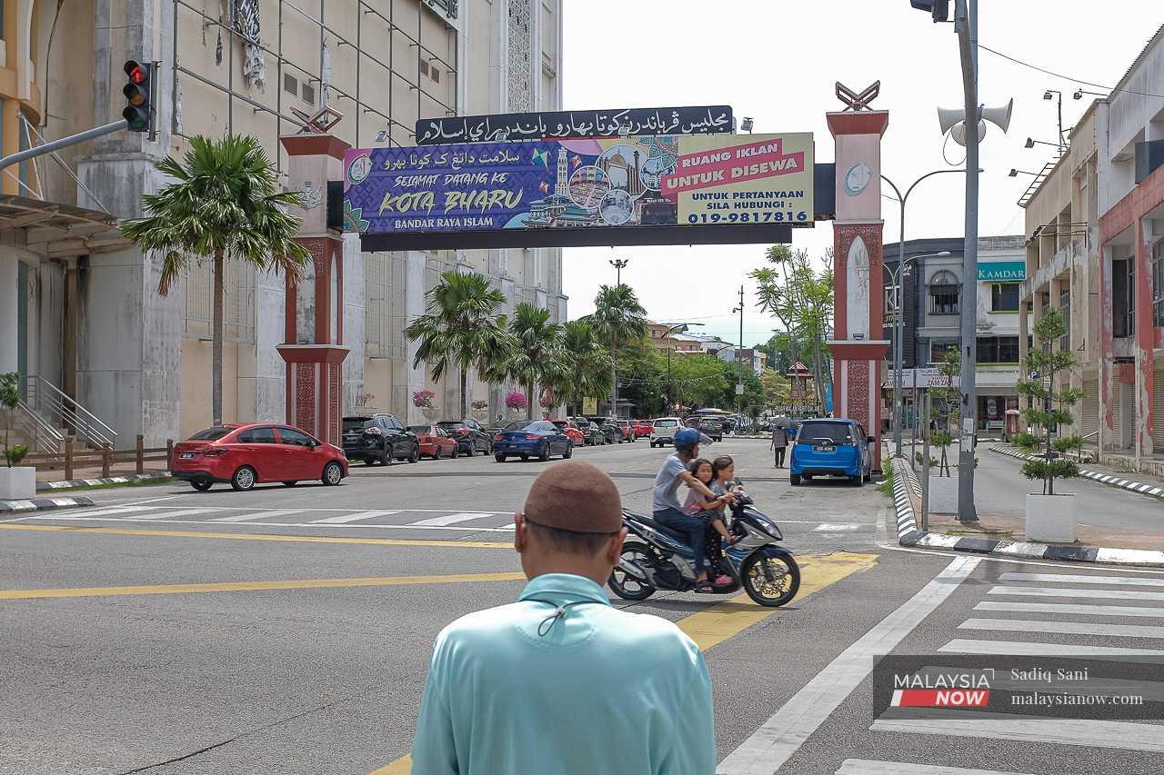 A man waits to cross a road near the gateway in the centre of Kota Bharu city. 