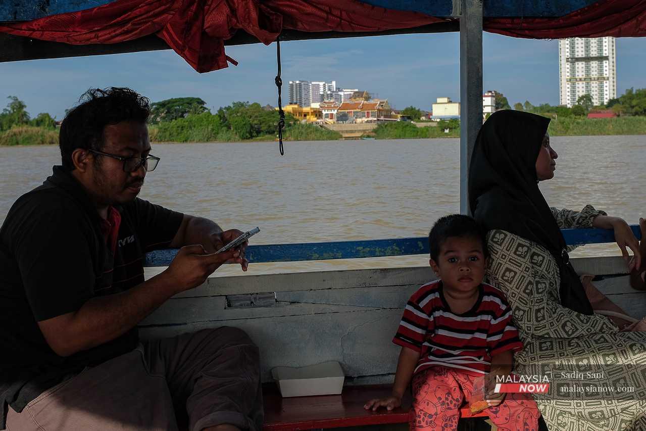 A couple with their young child cross the Kelantan River by boat. 