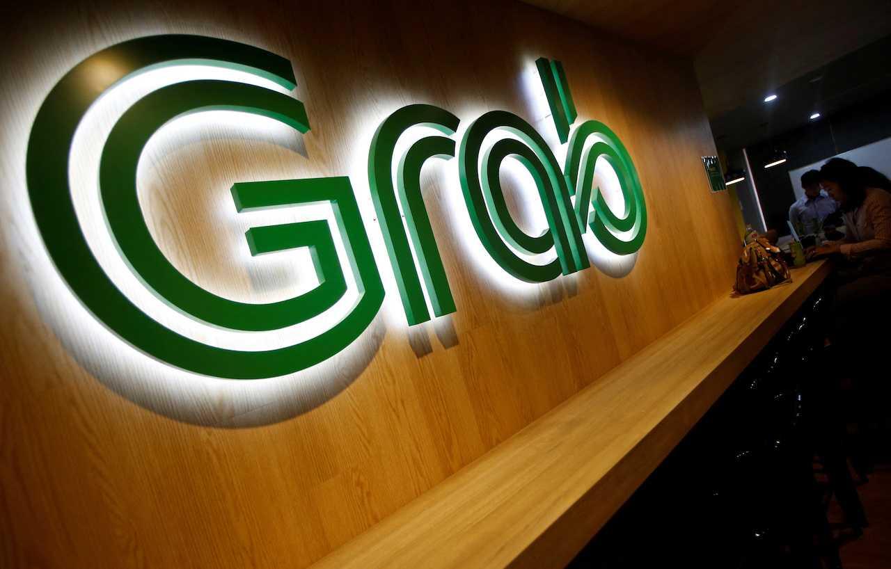 People sit next to a Grab signage in their office in Singapore
