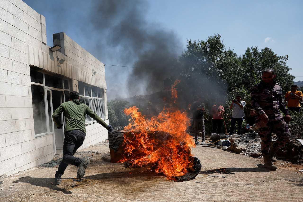 A Palestinian man runs near a burning object after an attack by Israeli settlers, near Ramallah, in the Israeli-occupied West Bank, June 21. Photo: Reuters