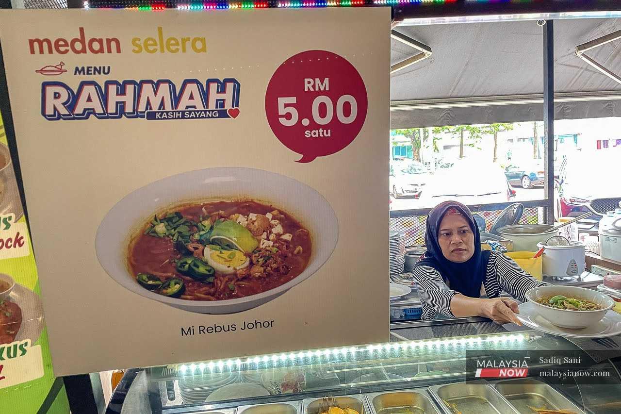 Seorang pekerja menghidangkan Menu Rahmah untuk pelanggan di sebuah kedai makan di Subang, Selangor.