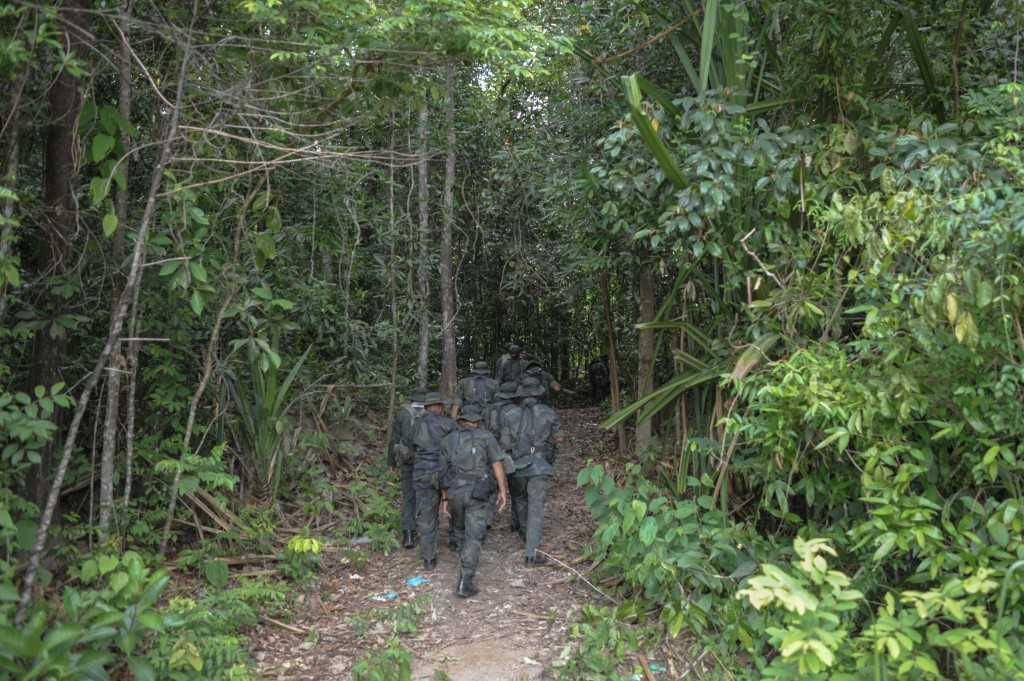 This photo taken on May 28, 2015 shows police personnel walking towards the dense jungle area in Wang Kelian that leads to an abandoned migrant camp, where some 37 graves were detected in Perlis, which borders Thailand. Photo: AFP
