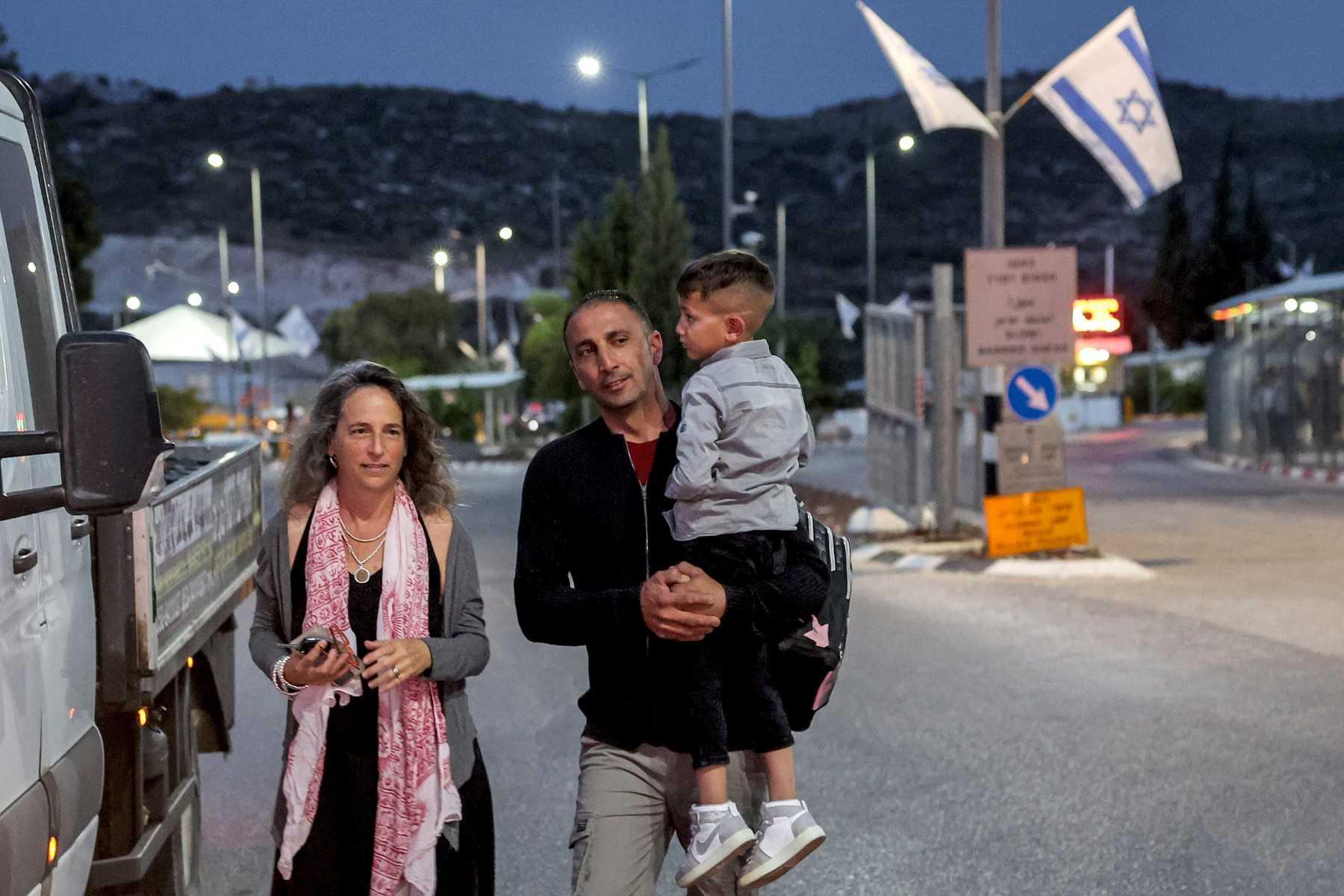 Adam Abu al-Rob, a six-year-old Palestinian eye cancer patient, is carried by his father Mamoun as they meet with Israeli NGO volunteer Yael Noy at the Rehan checkpoint between Israel and the occupied West Bank, driven by her on their way from the Palestinian village of Jalbun to Shiba Hospital Tel Hashomer near Tel Aviv, on May 22. Photo: AFP