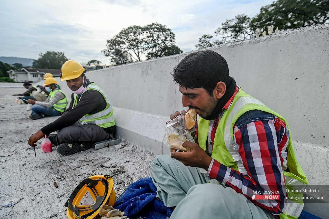 Pekerja asing menjamah makanan bagi mengalas perut ketika berehat di tapak pembinaan di Kuala Lumpur.