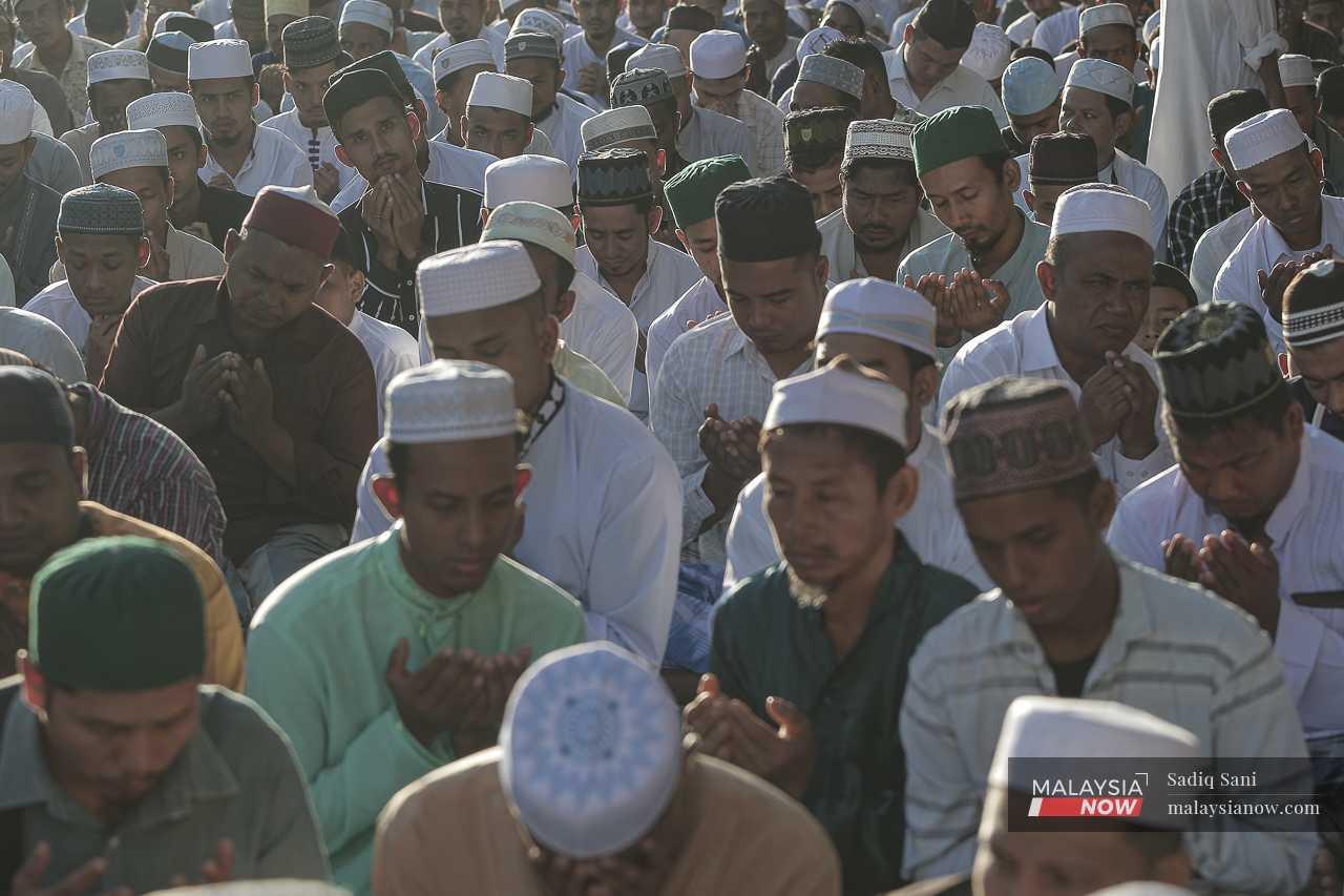 Rohingya men raise their hands in prayer.