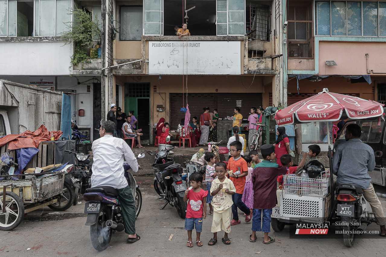 Rohingya children gather around an ice-cream vendor as the adults continue their conversations. 