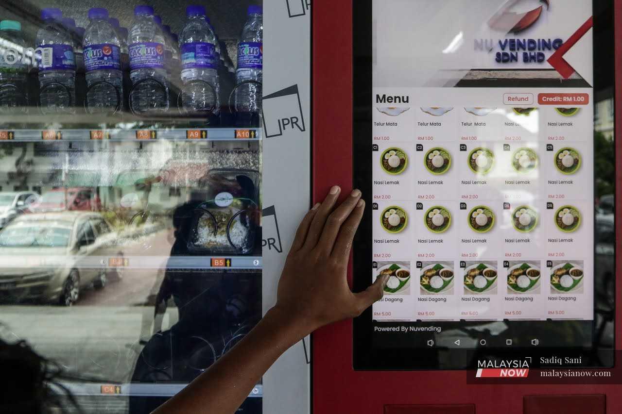 A customer scrolls through the menu on a vending machine at the Cempaka LRT station, provided by the economy ministry under the People's Income Initiative programme.