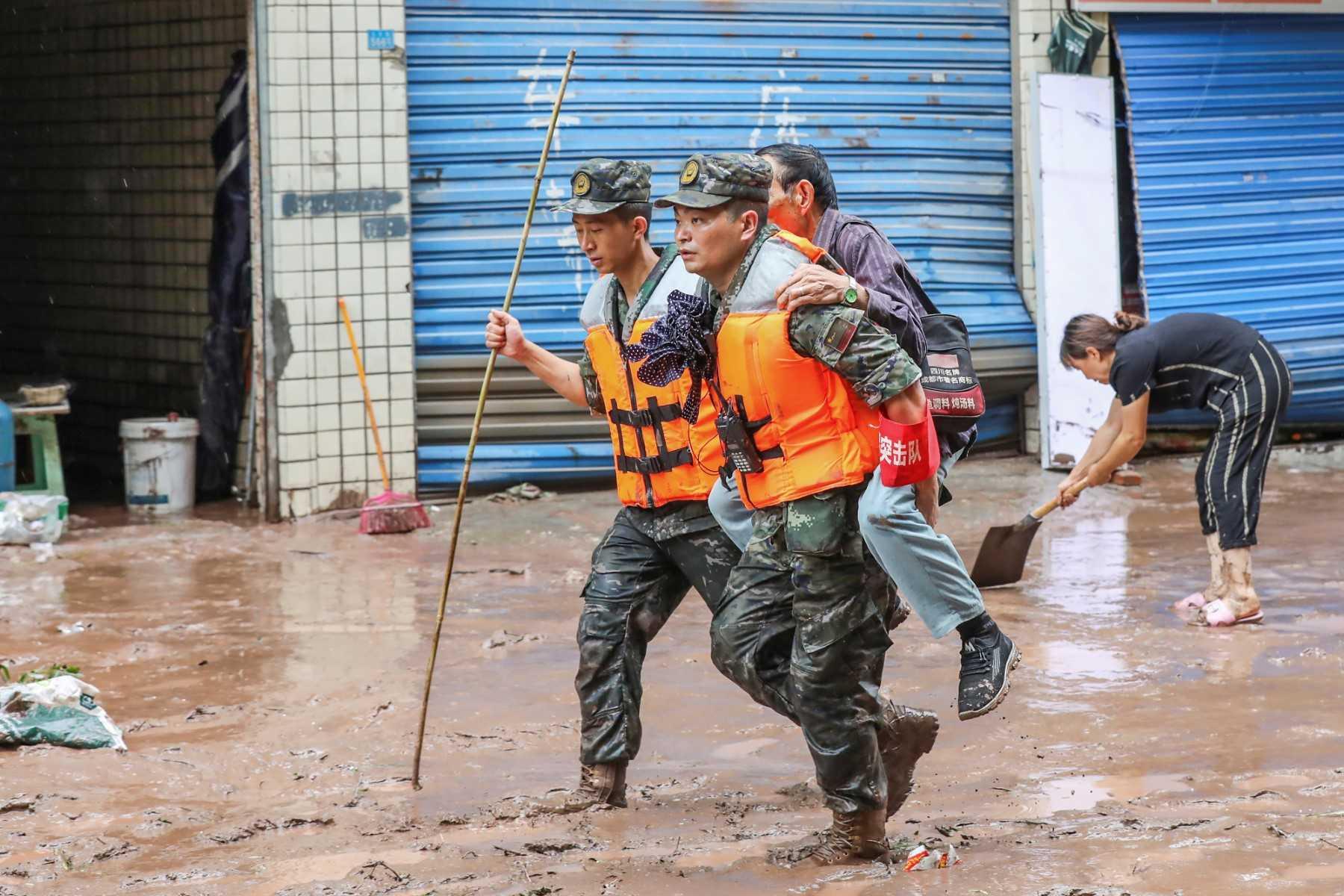 This file photo taken on July 4, shows paramilitary policemen evacuating a resident after flooding caused by heavy rains in China's southwestern Chongqing. Photo: AFP