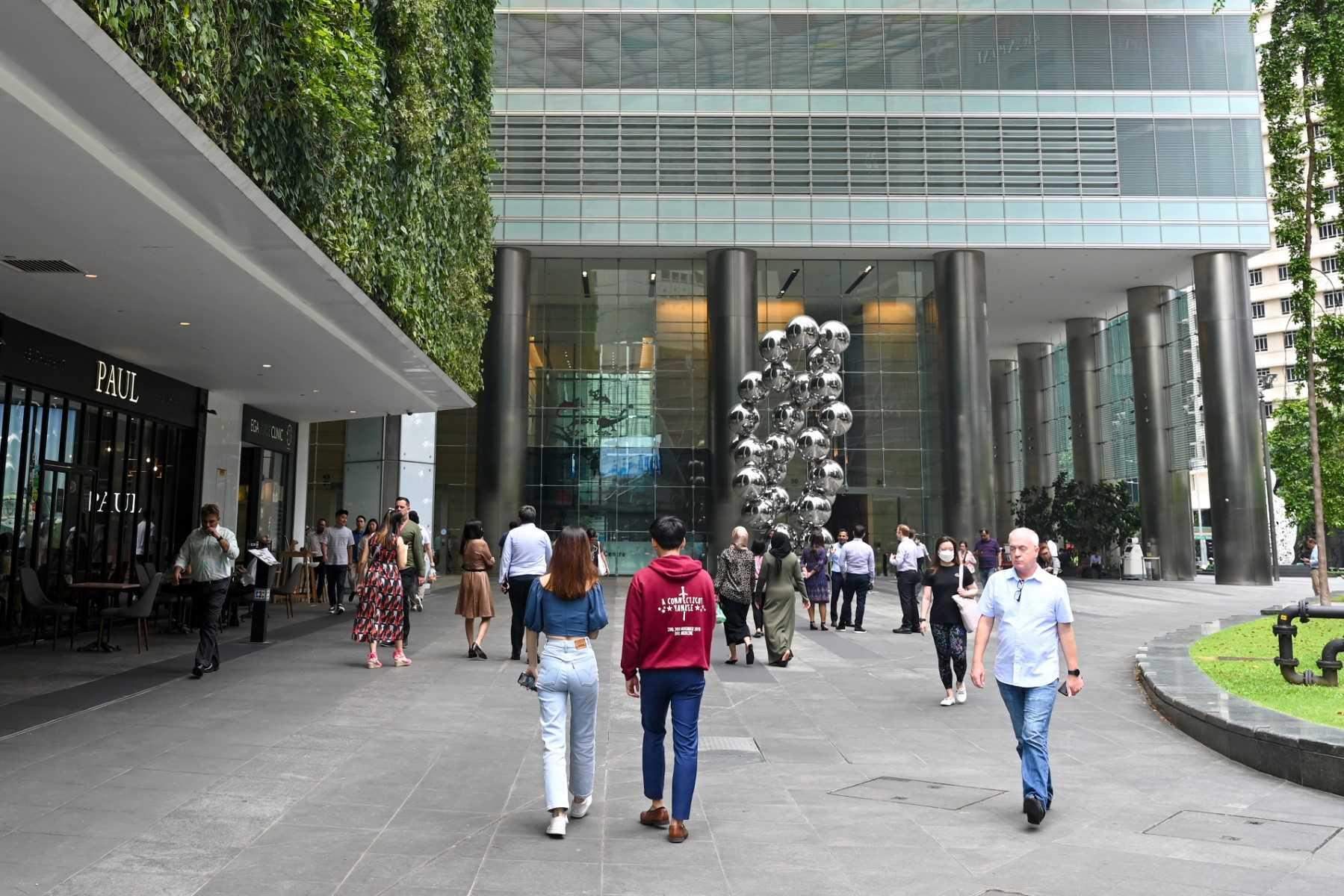 Orang ramai berjalan keluar sewaktu rehat tengah hari di daerah perniagaan kewangan Raffles Place di Singapura pada 26 Jun. Gambar: AFP