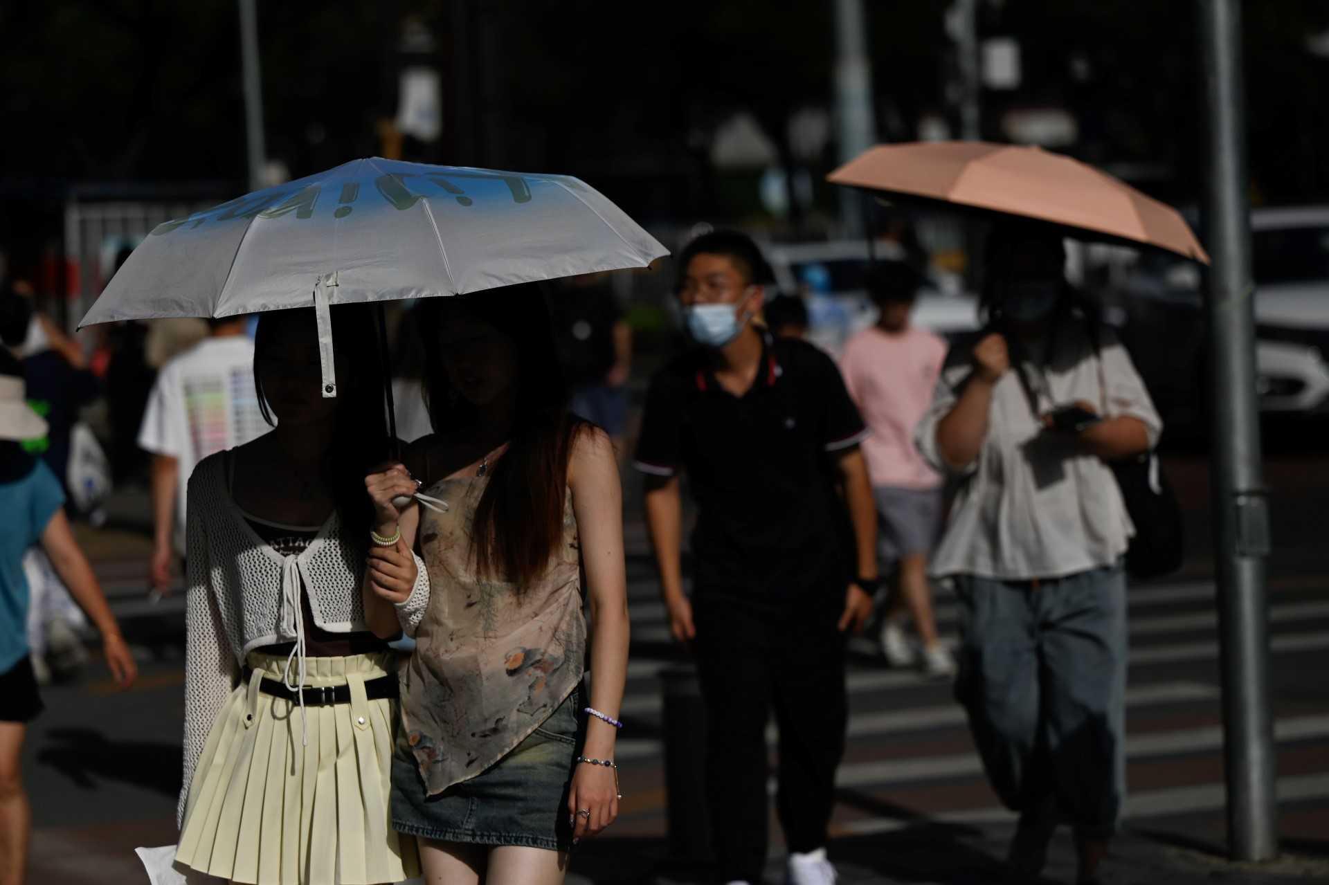 People walk along a street amid hot weather in Beijing on July 5. Photo: AFP