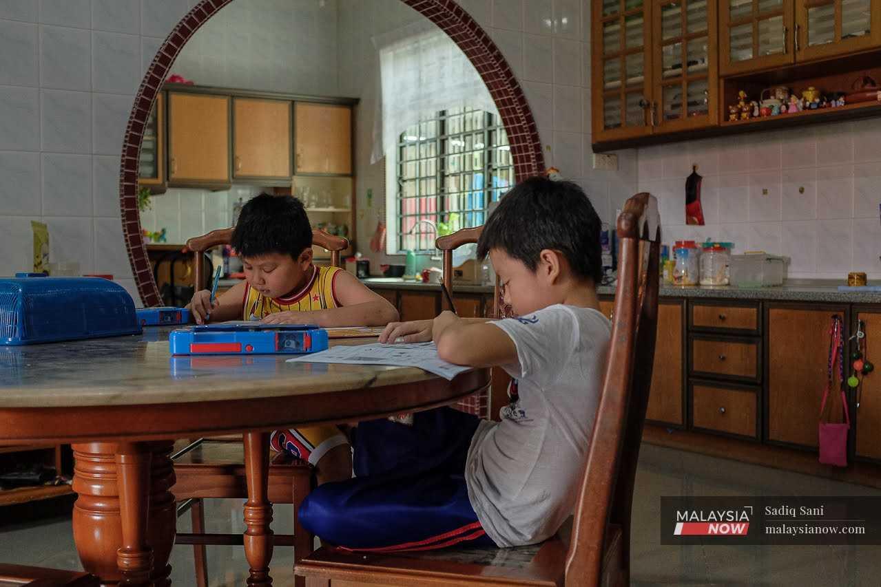 Brothers Wong Hao Xuan and Wong Hao Chen do their homework in the kitchen of their home in Seremban, Negeri Sembilan.