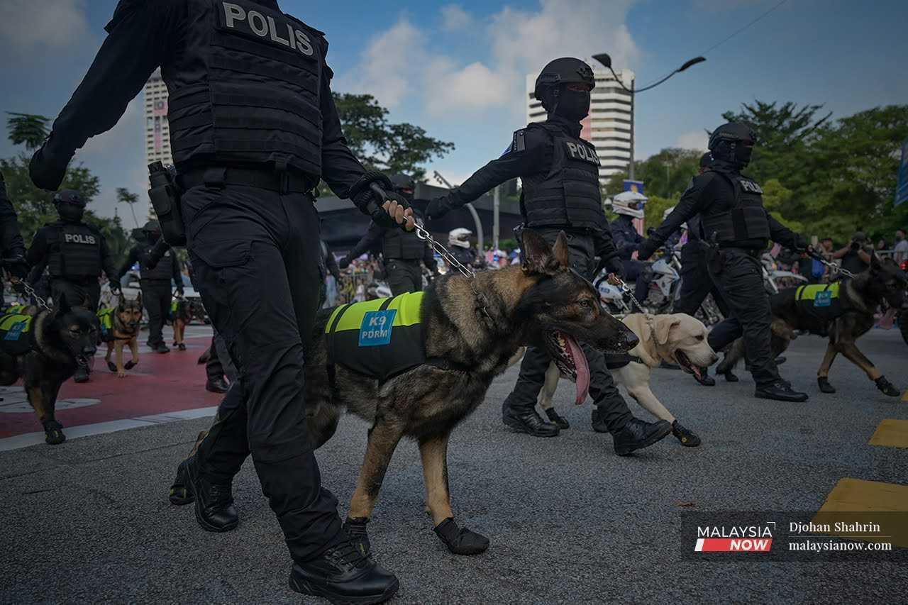 Anggota polis pasukan unit K9 membawa anjing pengesan ketika acara perbarisan sewaktu menyambut Hari Kemerdekaan ke-65 di Dataran Merdeka.