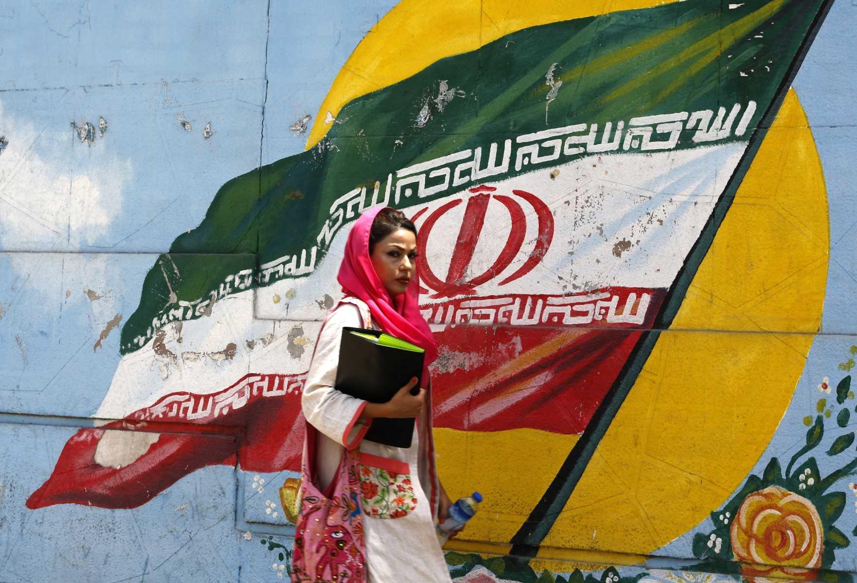 A woman walks in front of a mural painting depicting the Iranian flag, in the capital Tehran on Aug 6, 2018. Photo: AFP 