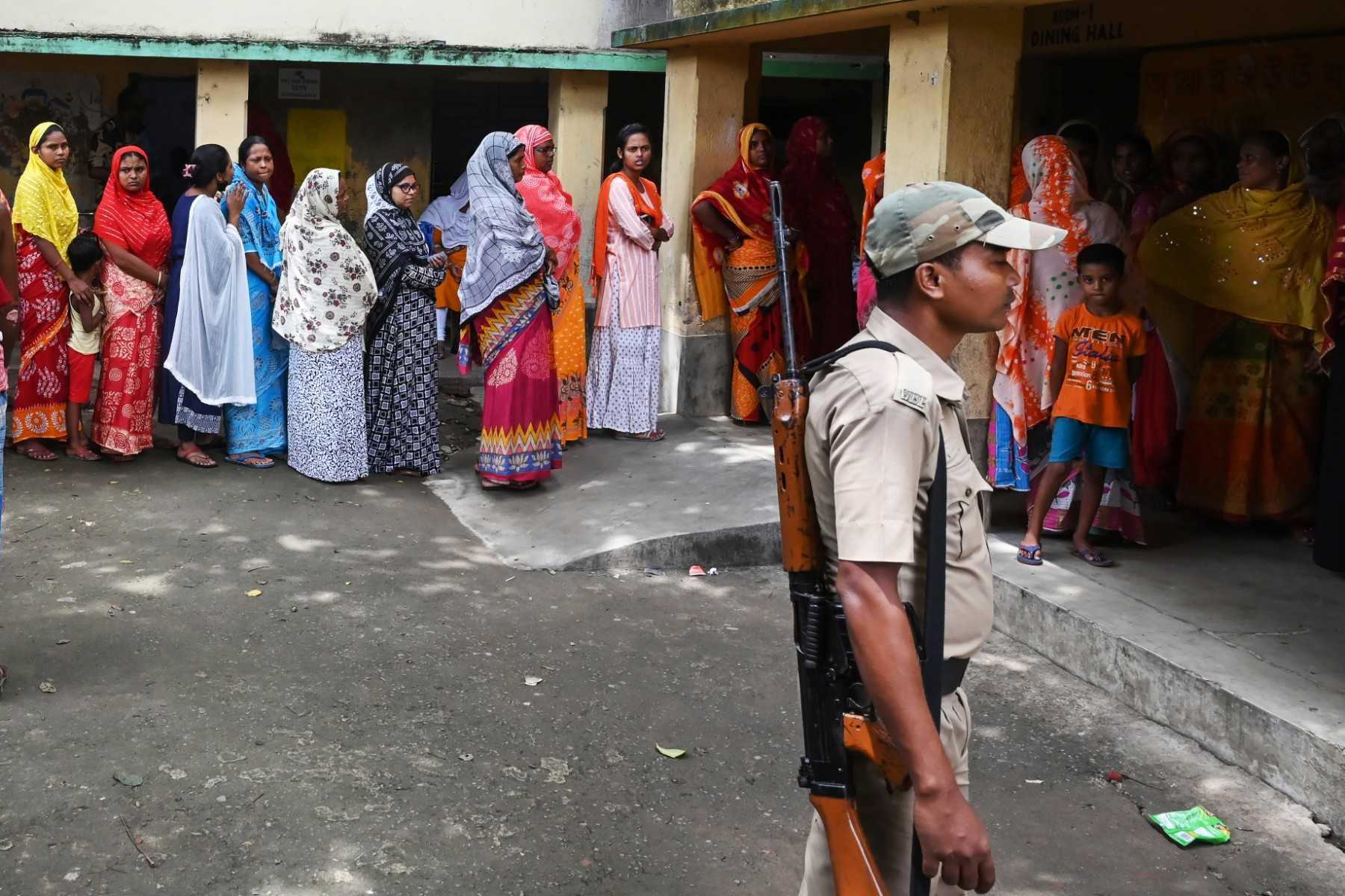 A police officer stands guard as people queue at a polling station to cast their vote in West Bengal's 'Panchayat' or local elections, on the outskirts of Kolkata on July 8. Photo: AFP