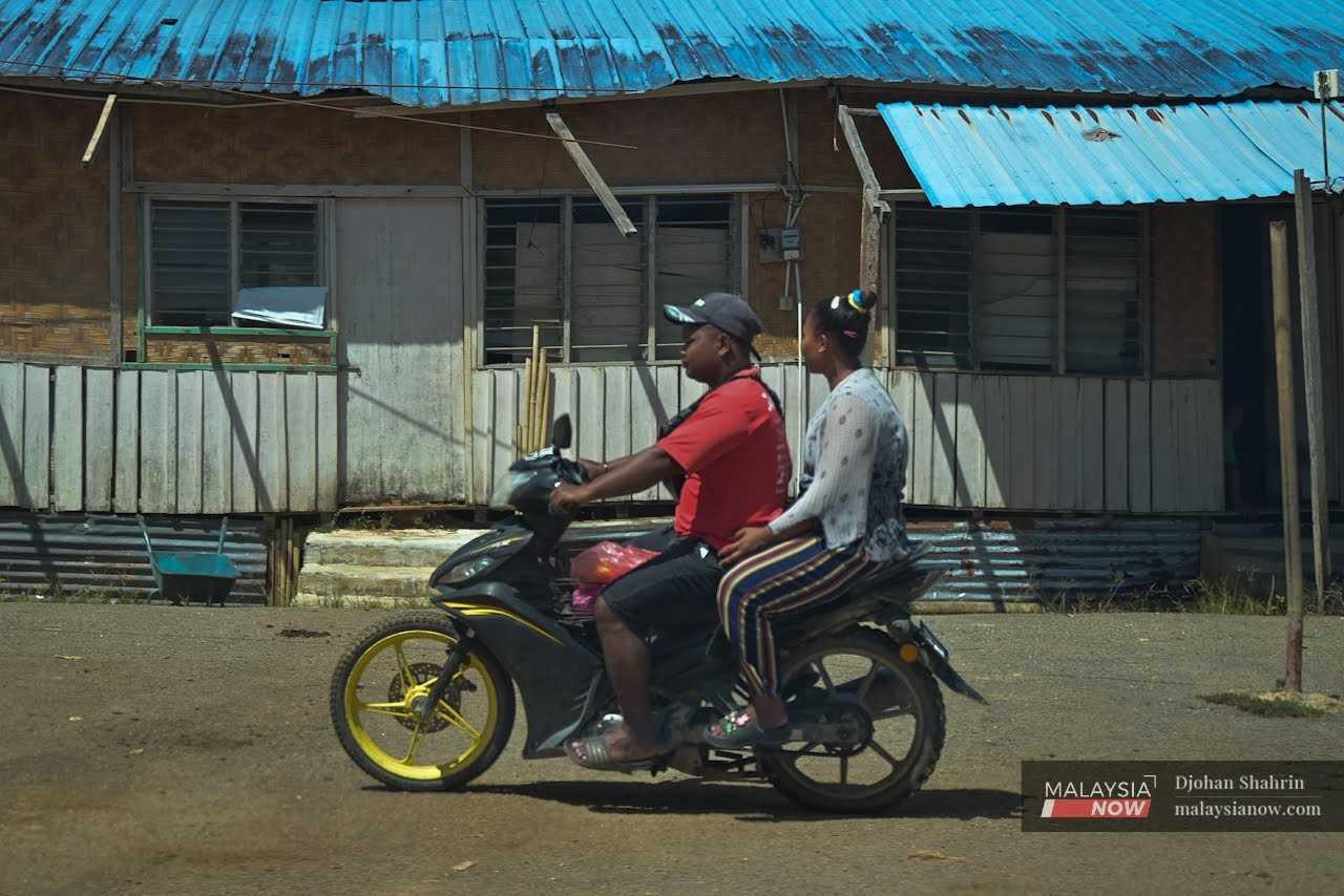 Orang Asli ride a motorcycle through their village in Tasik Banding, Hulu Perak.