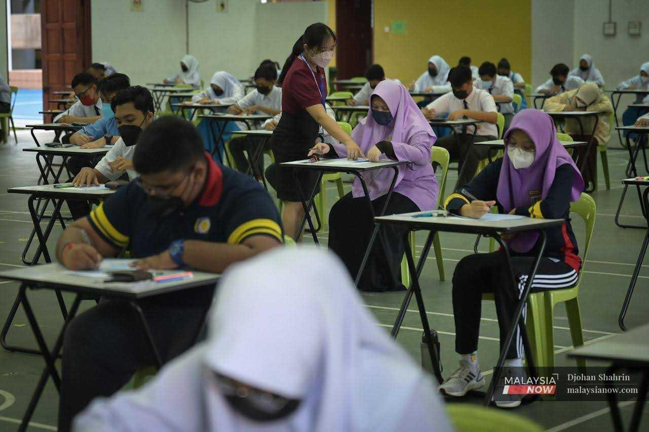 An invigilator helps a student sitting for an examination at a school in Sentul, Kuala Lumpur, in this file photo.