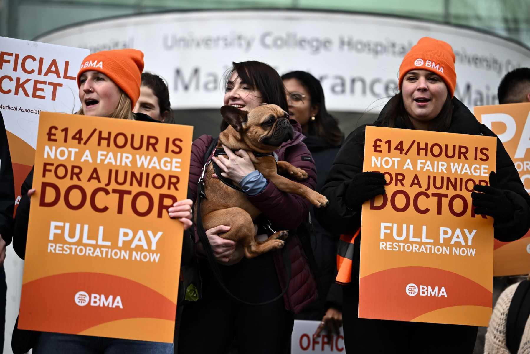 People hold British Medical Association branded placards calling for better pay, as they stand on a picket line outside University College Hospital in central London on April 12. Photo: AFP