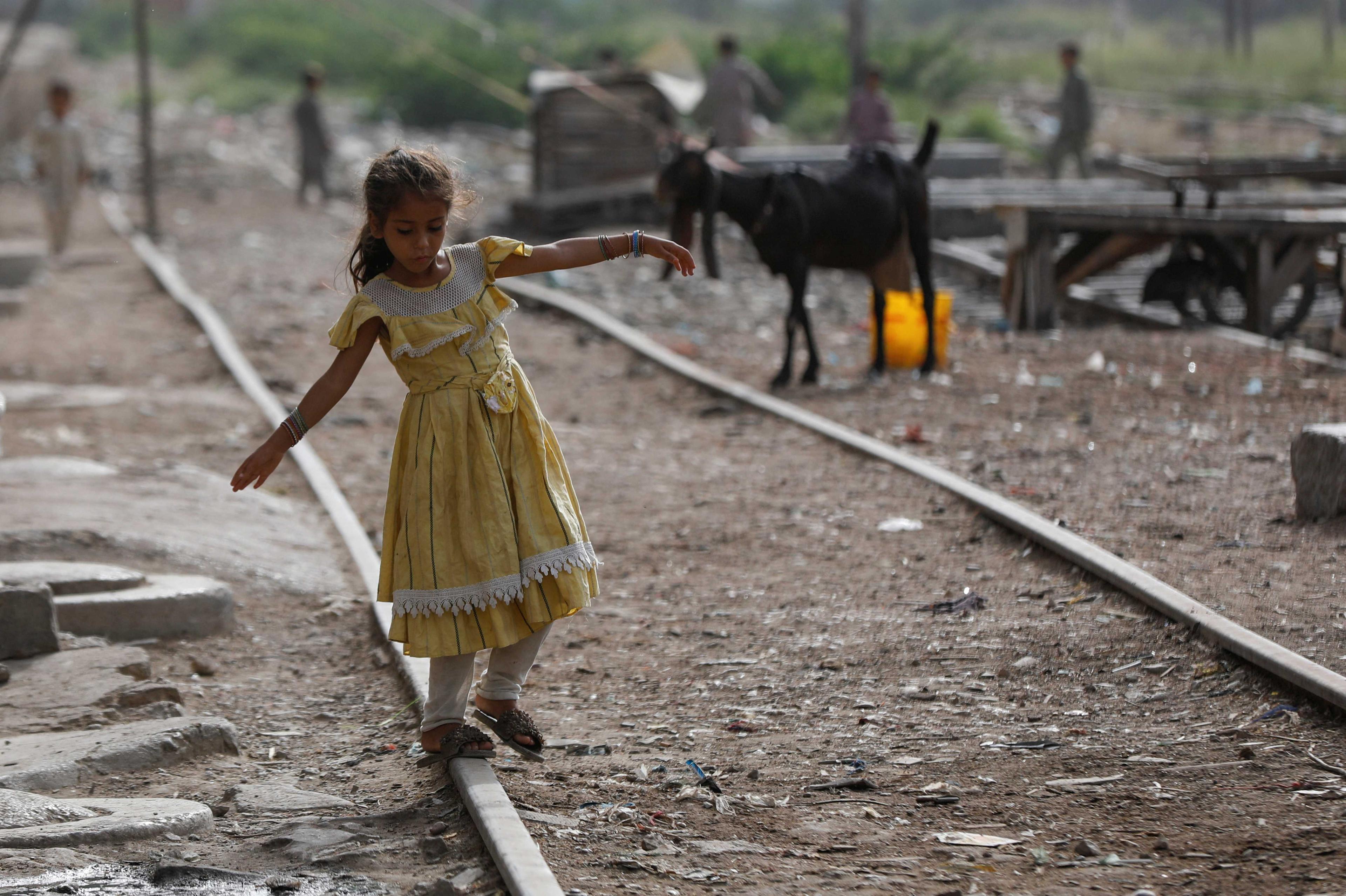 A girl balances herself while walking on an abandoned railway track in a slum area in Karachi, Pakistan July 10. Photo: Reuters