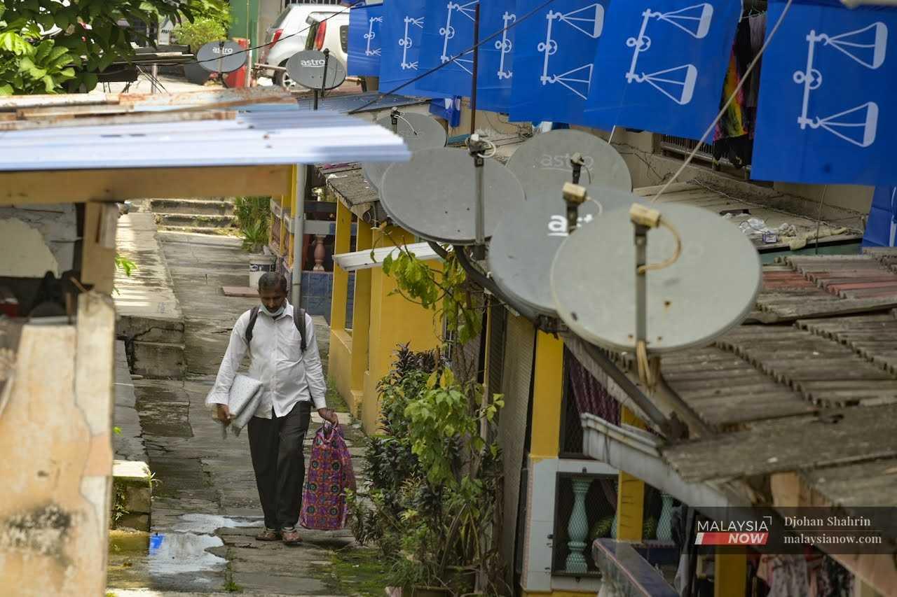 A man passes below rows of Barisan Nasional flags at a low-cost housing project ahead of the 15th general election last year in Jalan Enggang, Keramat in Kuala Lumpur.