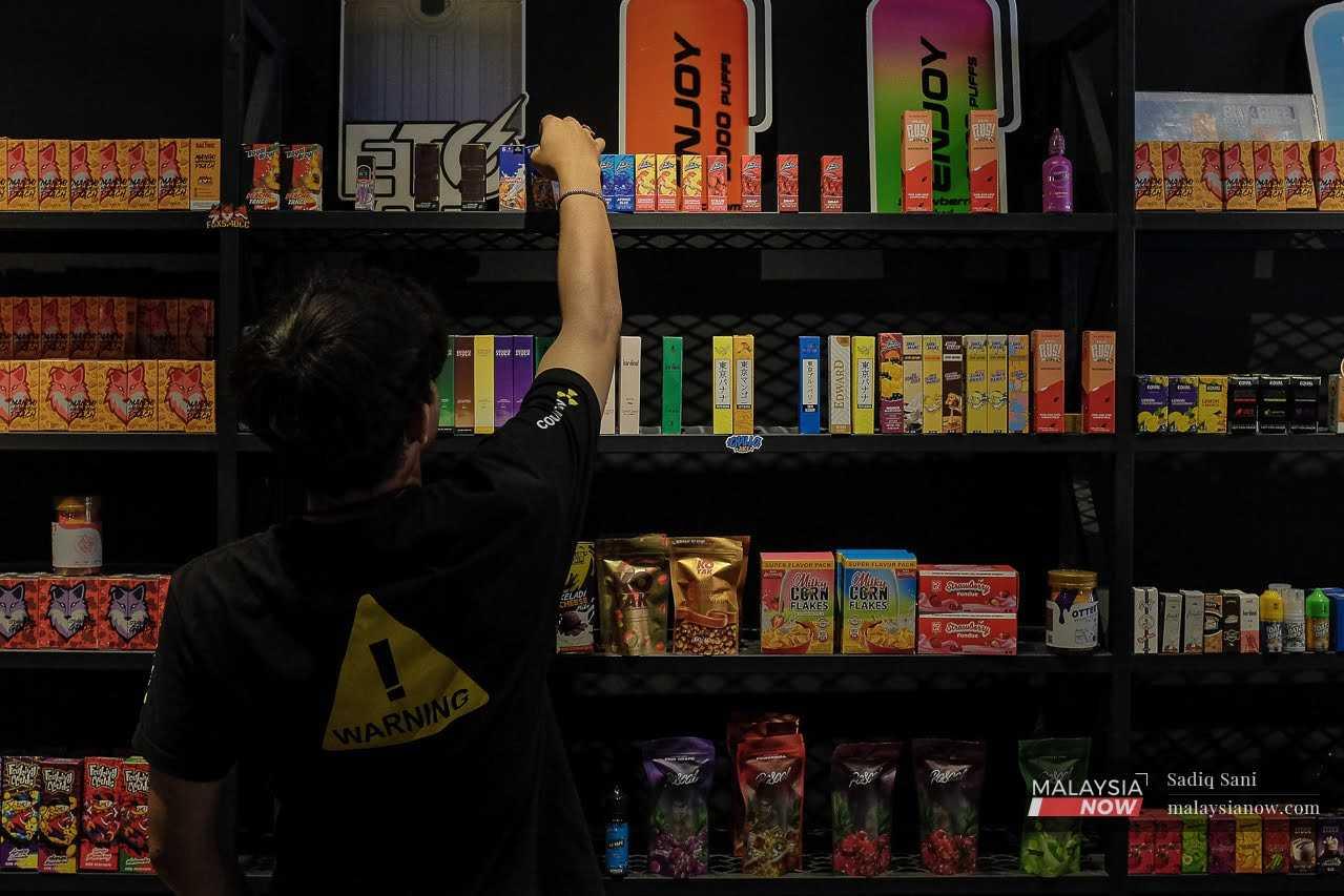 A worker reaches for flavoured e-cigarette pods at a vape store in Kuala Lumpur.