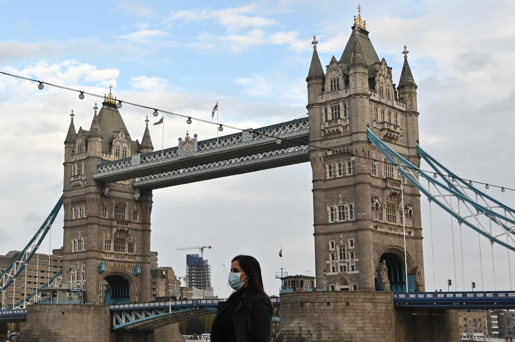 A pedestrian wearing a mask because of Covid-19 walks past Tower Bridge in London on Nov 1, 2020. Photo: AFP 