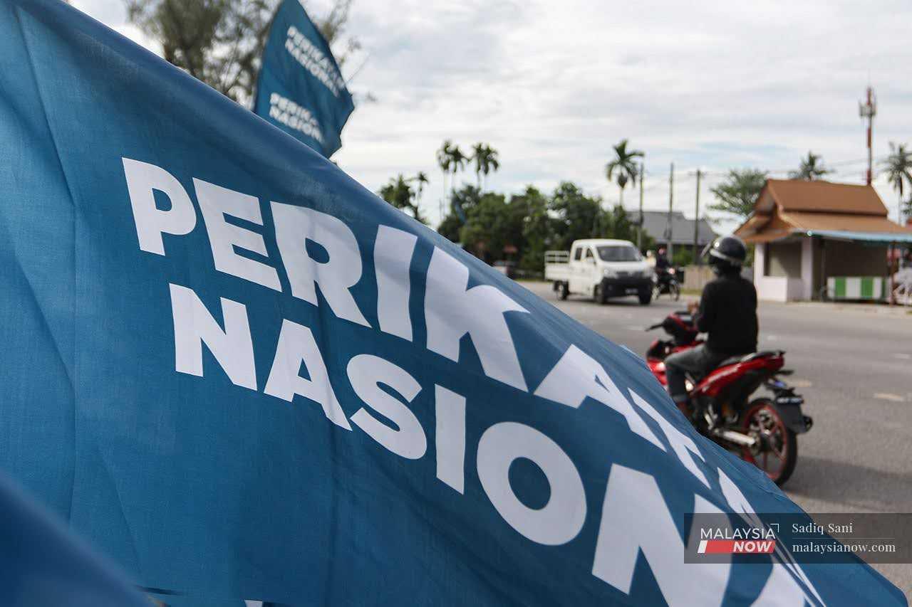 A motorcyclist rides past Perikatan Nasional flags ahead of the 15th general election in November 2022. 