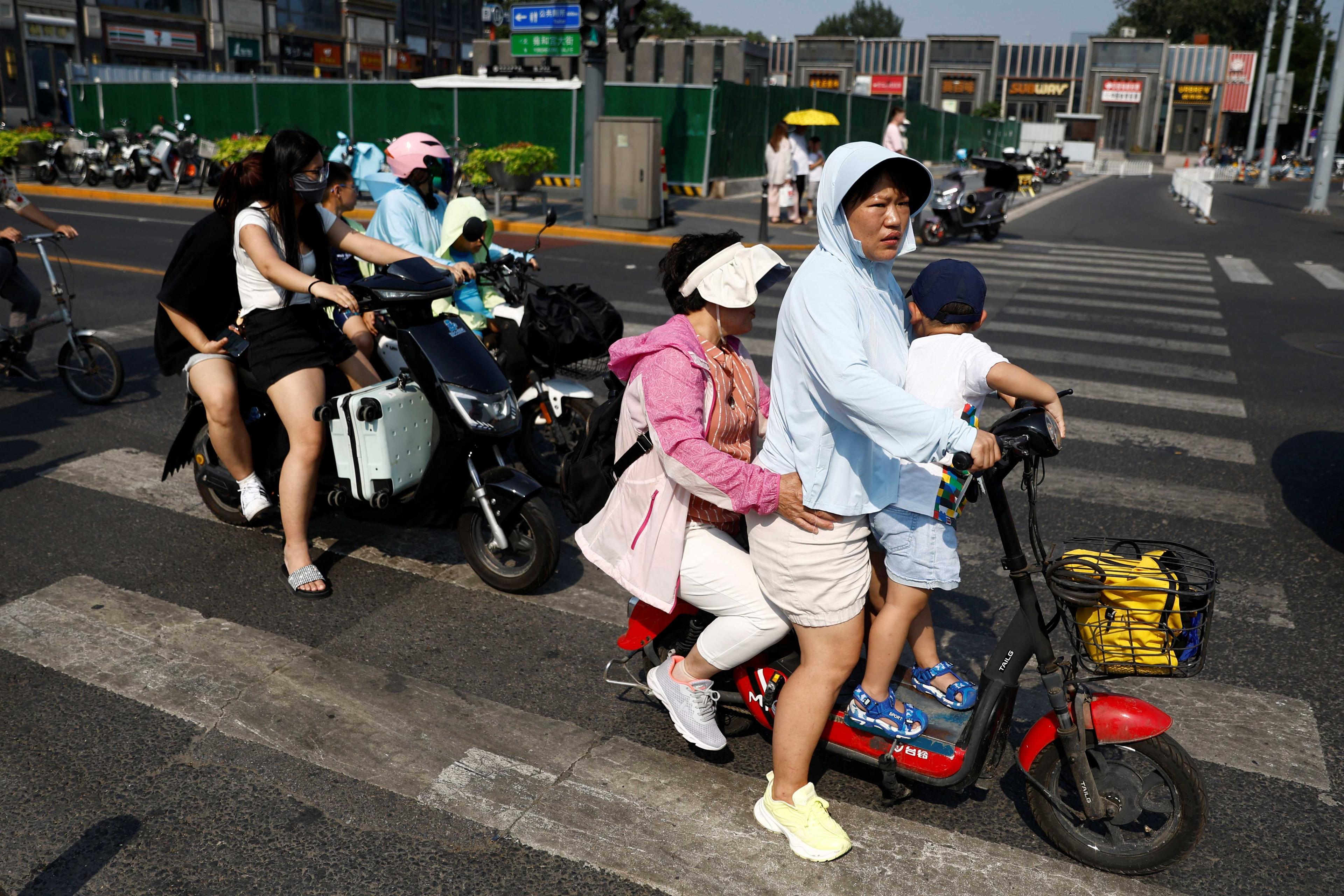 People ride on scooters amid a yellow alert for heatwave, at a street in Beijing, China July 19. Photo: Reuters