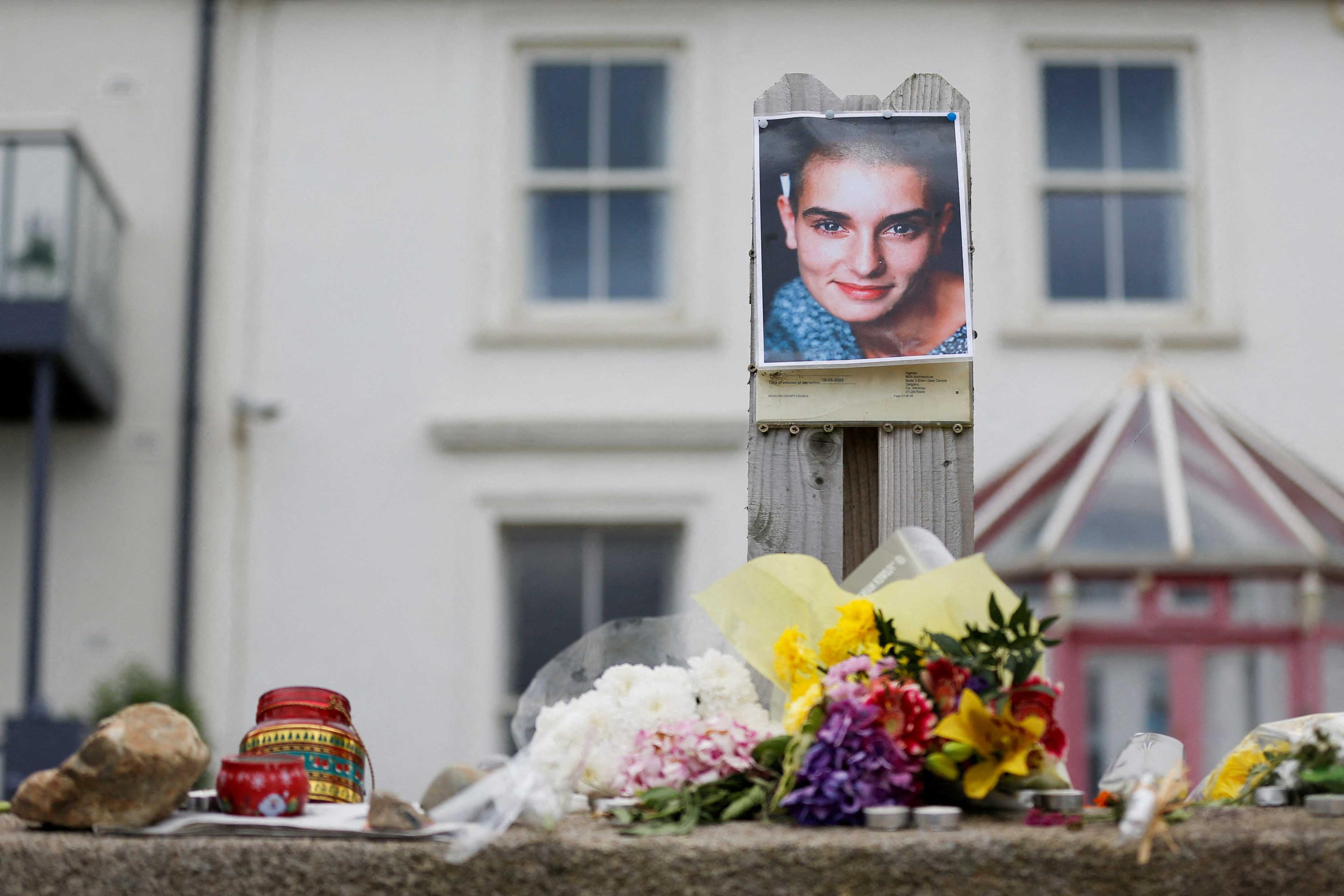 A picture of late singer Sinead O'Connor, who died at the age of 56, is placed around floral tributes outside her former Irish home, in the seaside town of Bray in County Wicklow, Ireland, July 27. Photo: Reuters