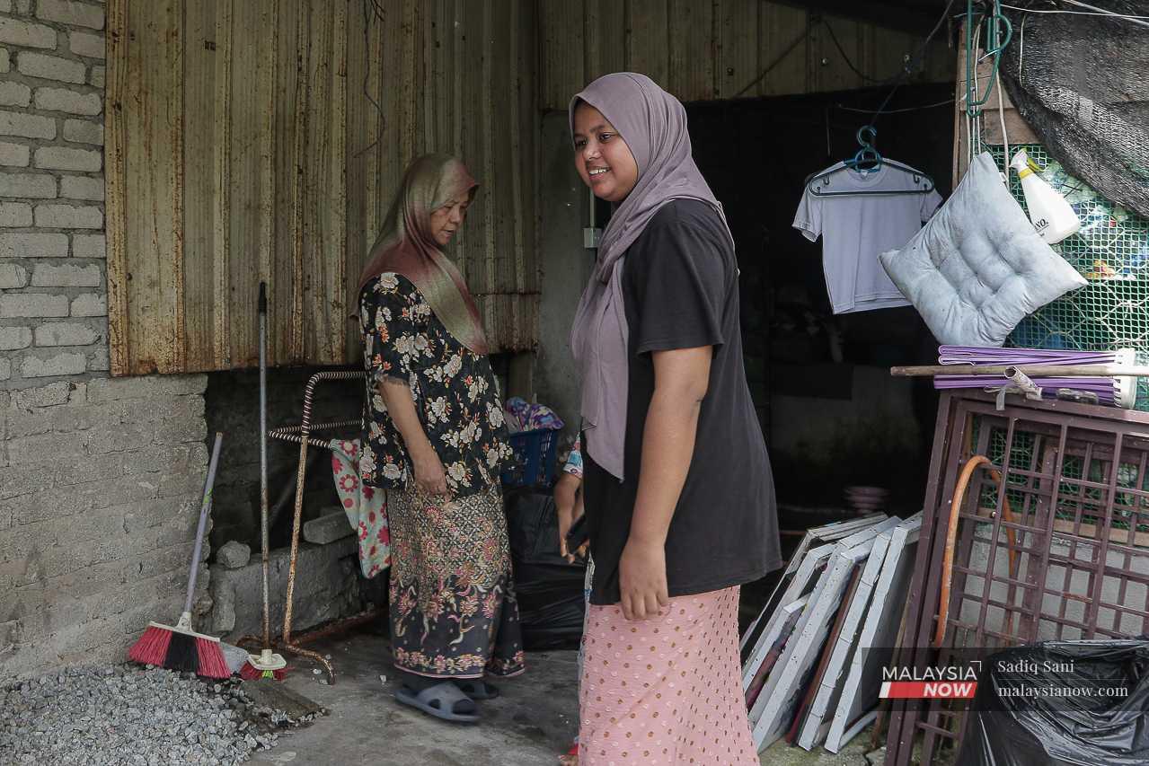 A woman and her daughter inspect the cracked floor at the back of their house.