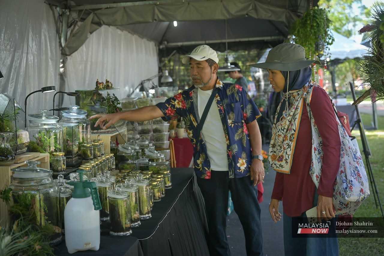A customer listens to Aziz as he talks about the selection of terrariums on display at the exhibition.