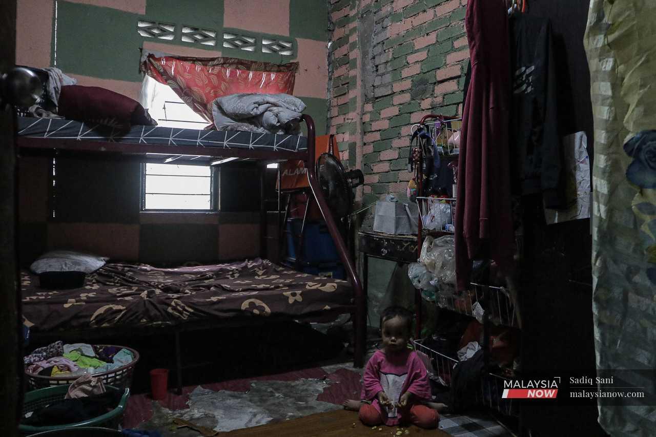 A young girl sits in a room where the walls have cracked due to what the residents say was an explosion at the nearby construction site. 
