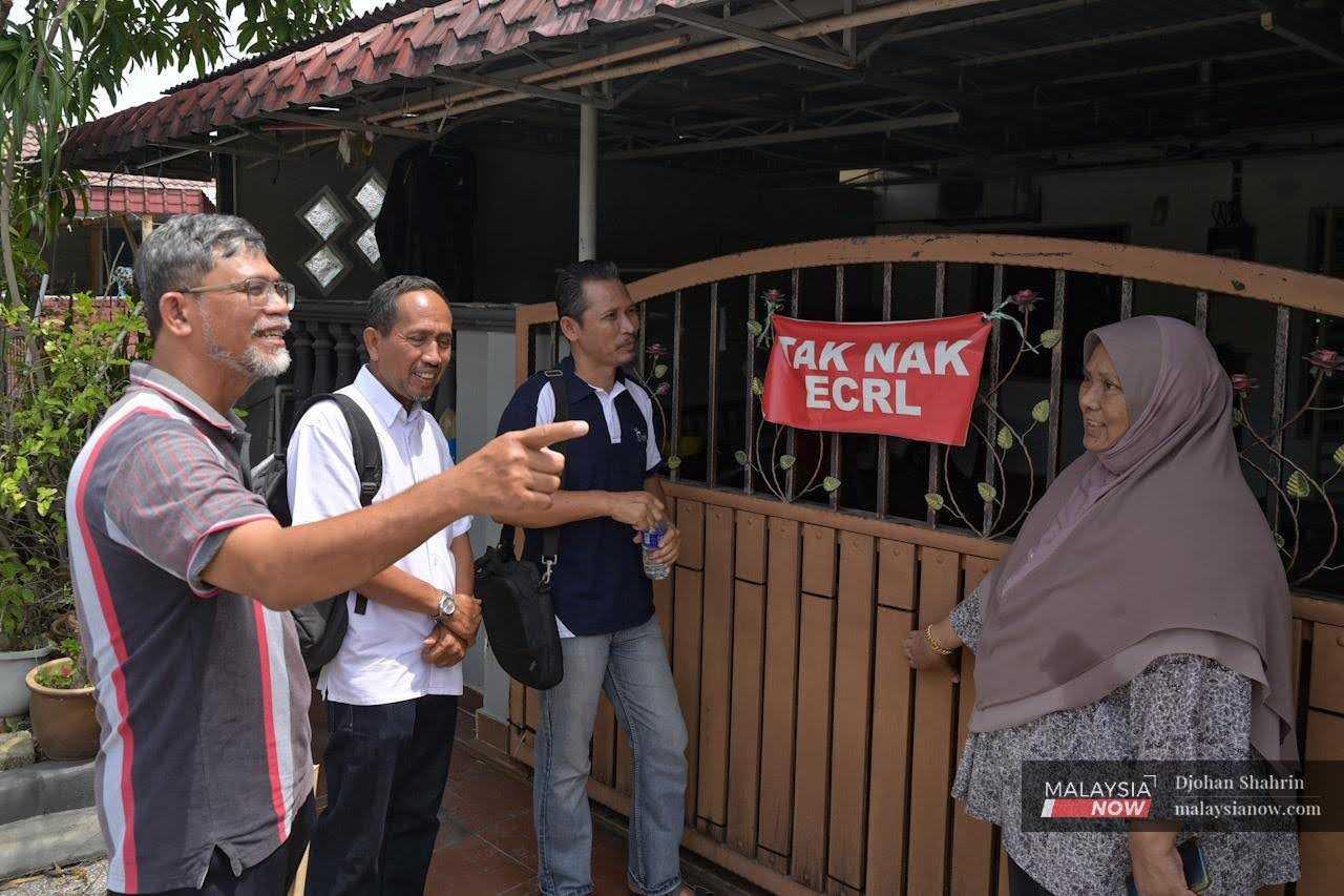 Seorang penduduk, Rogayah Mat Jin mendengar penerangan dari Pengerusi dan ahli Jawatankuasa Bertindak tentang perkembangan terkini berkaitan isu Jajaran Projek Laluan Rel Pantai Timur (ECRL) di Taman Sungai Sireh, 25 Julai.