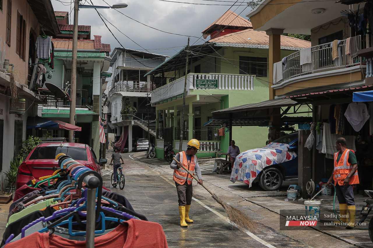 Pekerja binaan membersihkan jalan di Kampung Sungai Salak selepas limpahan lumpur dari tapak pembinaan berhampiran. 