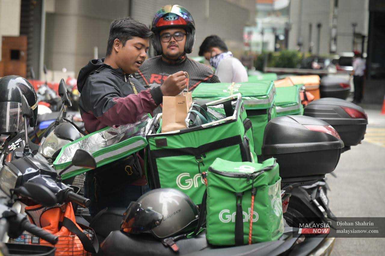 Penghantar makanan menunggu pesanan di sekitar pusat beli-belah di Bukit Bintang, Kuala Lumpur.