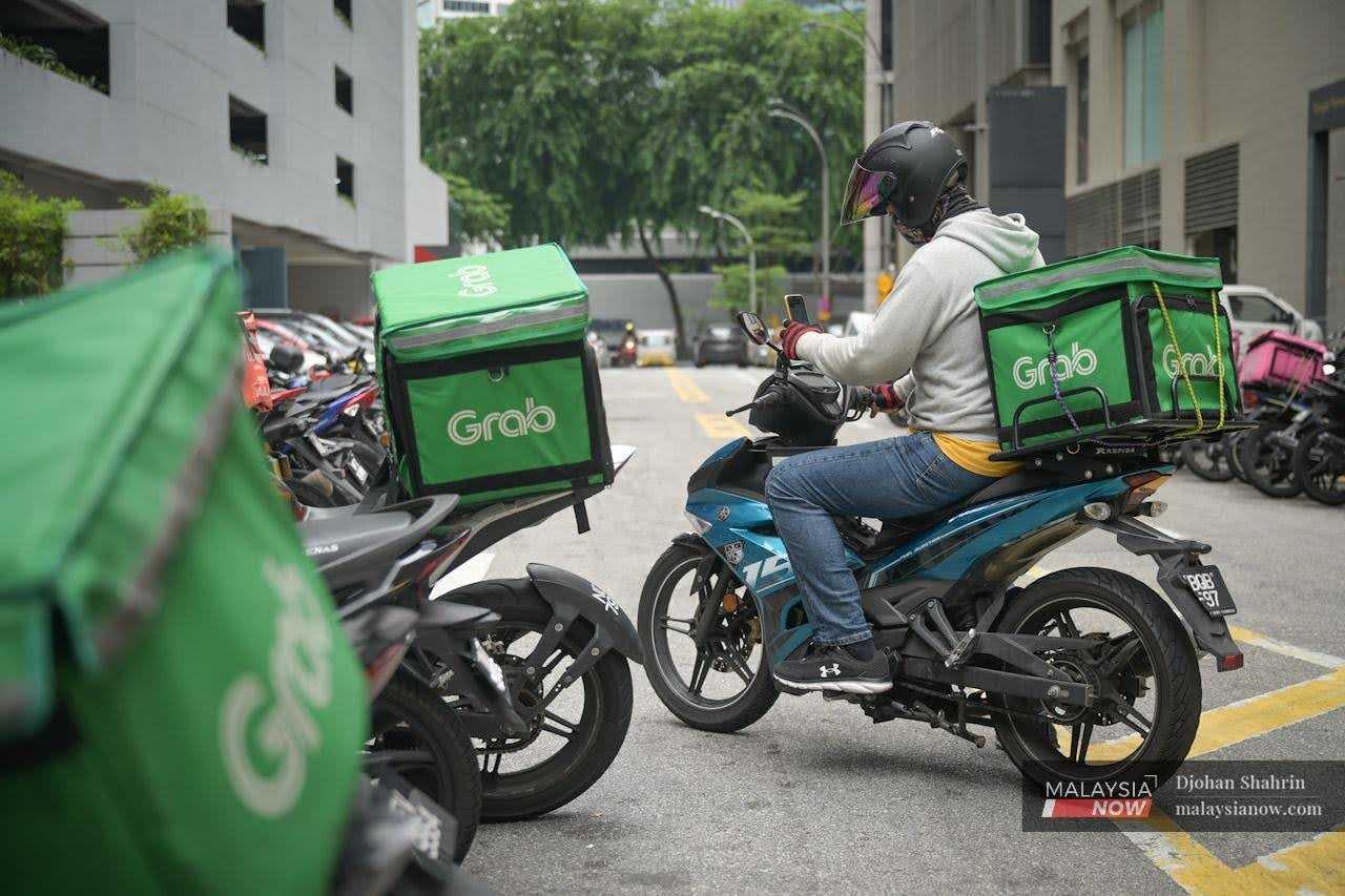 A Grab food delivery rider accepts orders on his mobile phone in the Bukit Bintang shopping district in Kuala Lumpur.