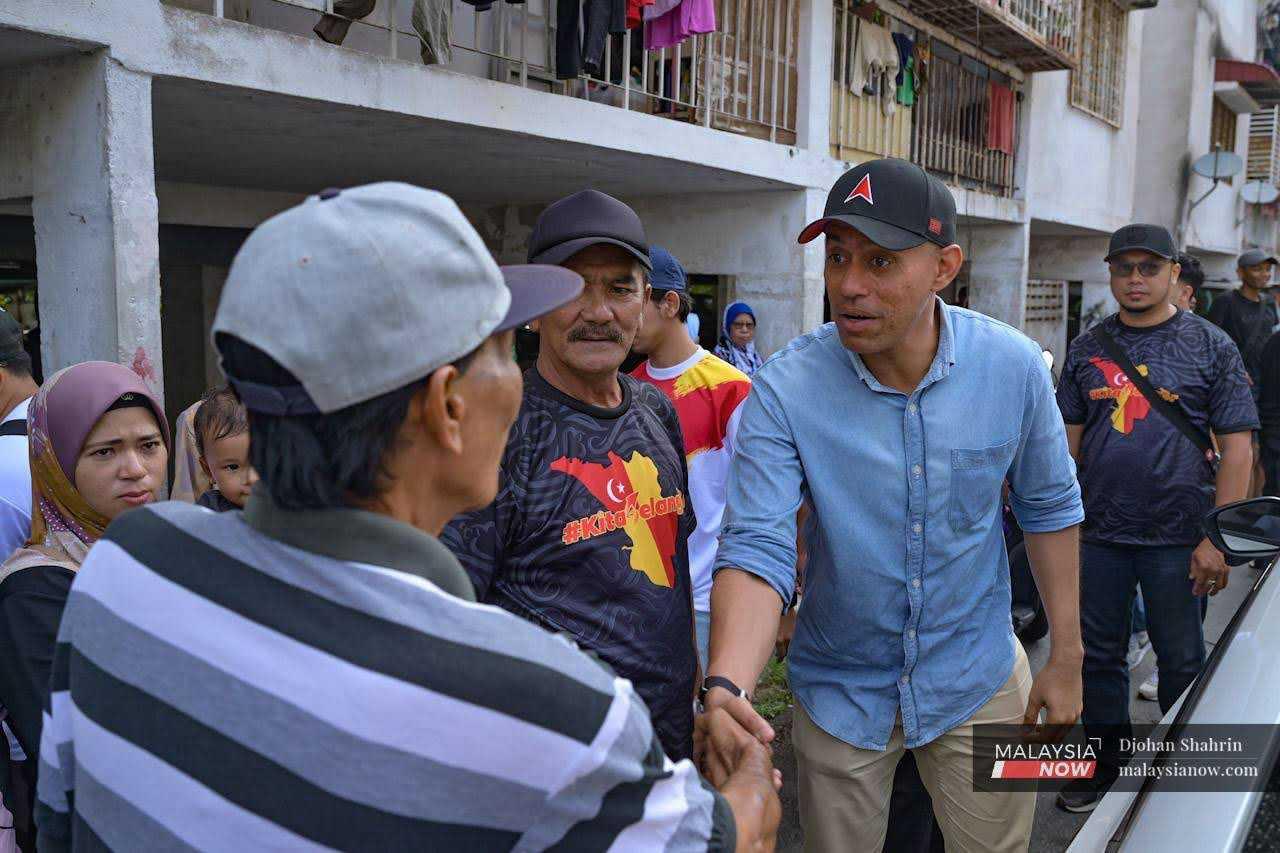 Pakatan Harapan candidate for Lembah Jaya, Syed Ahmad Abdul Rahman, better known as Altimet, shakes hands with a Taman Mulia Jaya resident during his visit to the area.