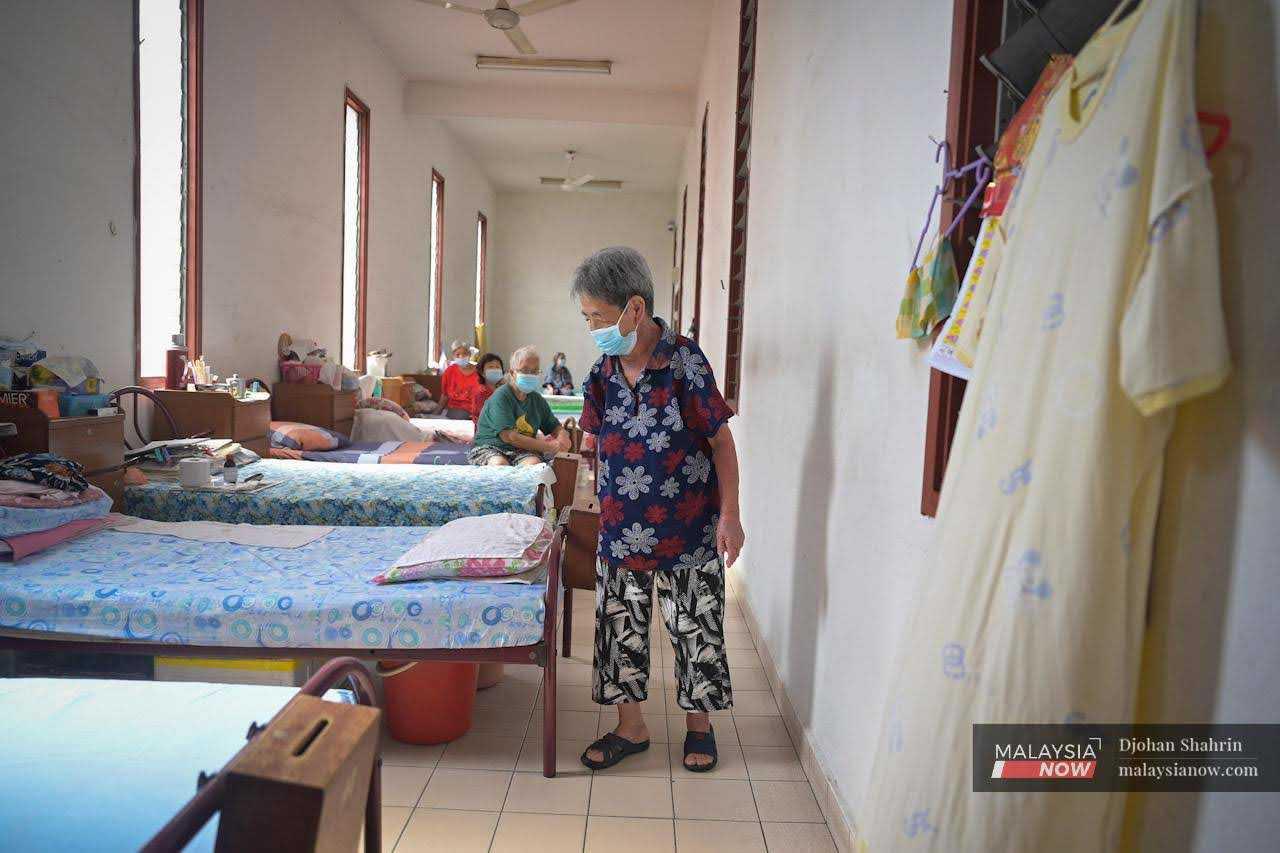 An elderly woman walks towards her bed at the old folks' home that was established in 1963, where a total of 50 men and women from all walks of life reside.