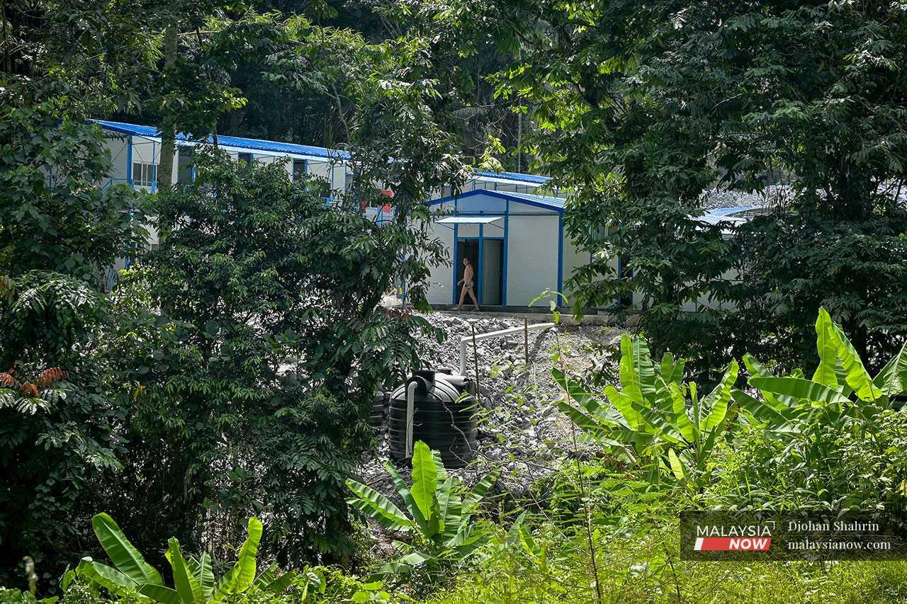 A worker leaves the toilet of the dormitory which now stands behind Tok Ulang's orchard.