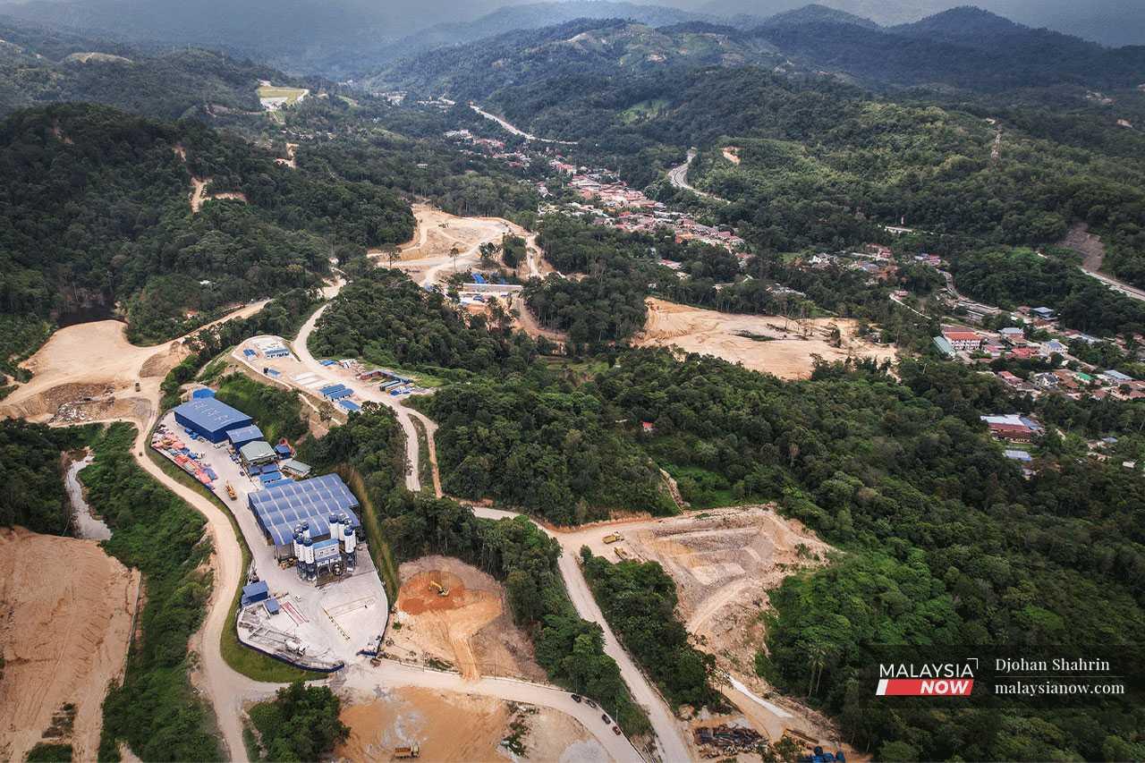 An aerial view of the ECRL construction site near Taman Permai Jaya, where heavy machinery is used to extract earth from the hills and chop down trees.