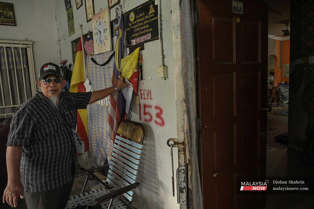 Village leader Mohmad Najib Mokhtar shows the sign painted in red on his wall which was done without his knowledge or consent.